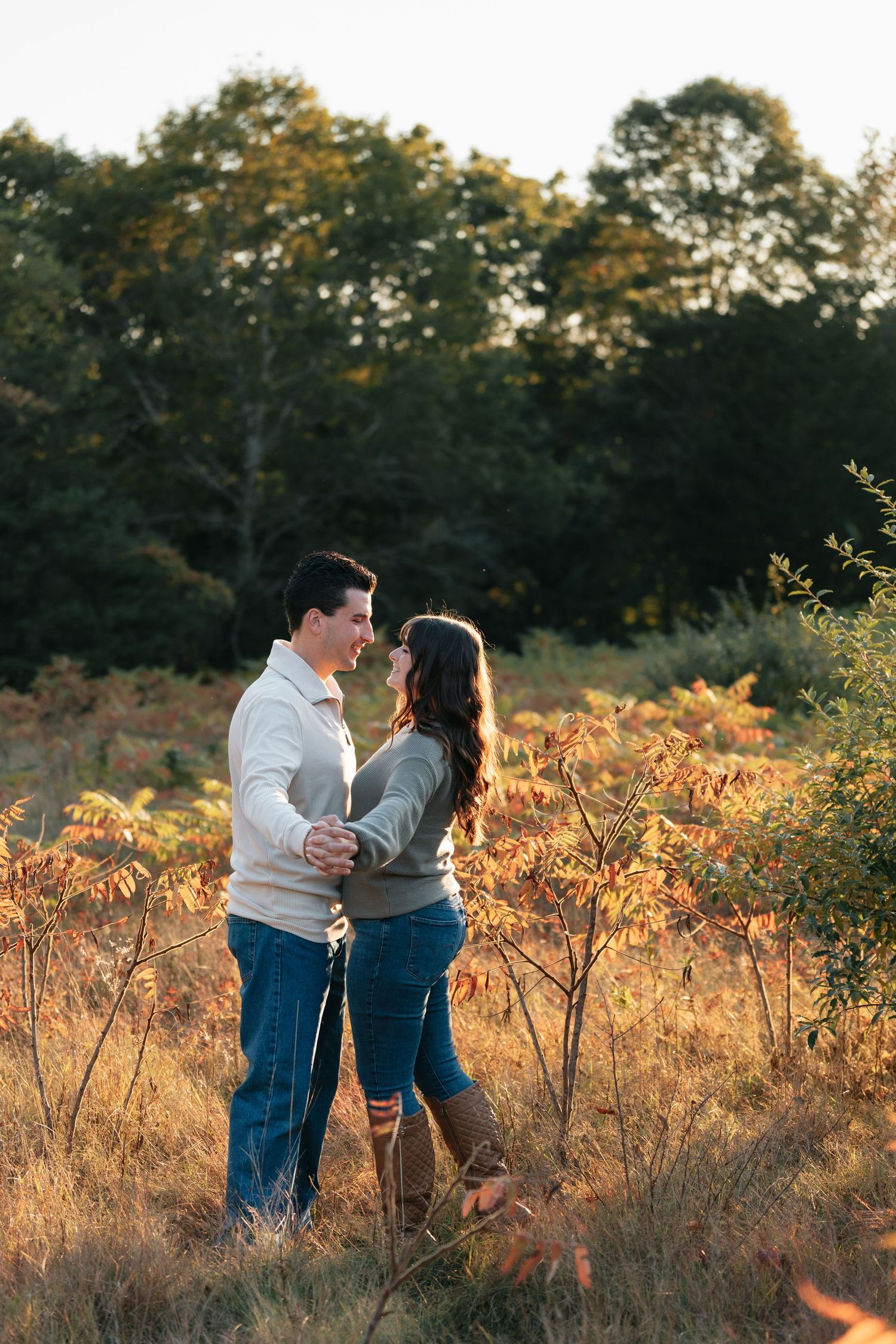 A couple shares an intimate moment in a field of tall grass during golden hour.