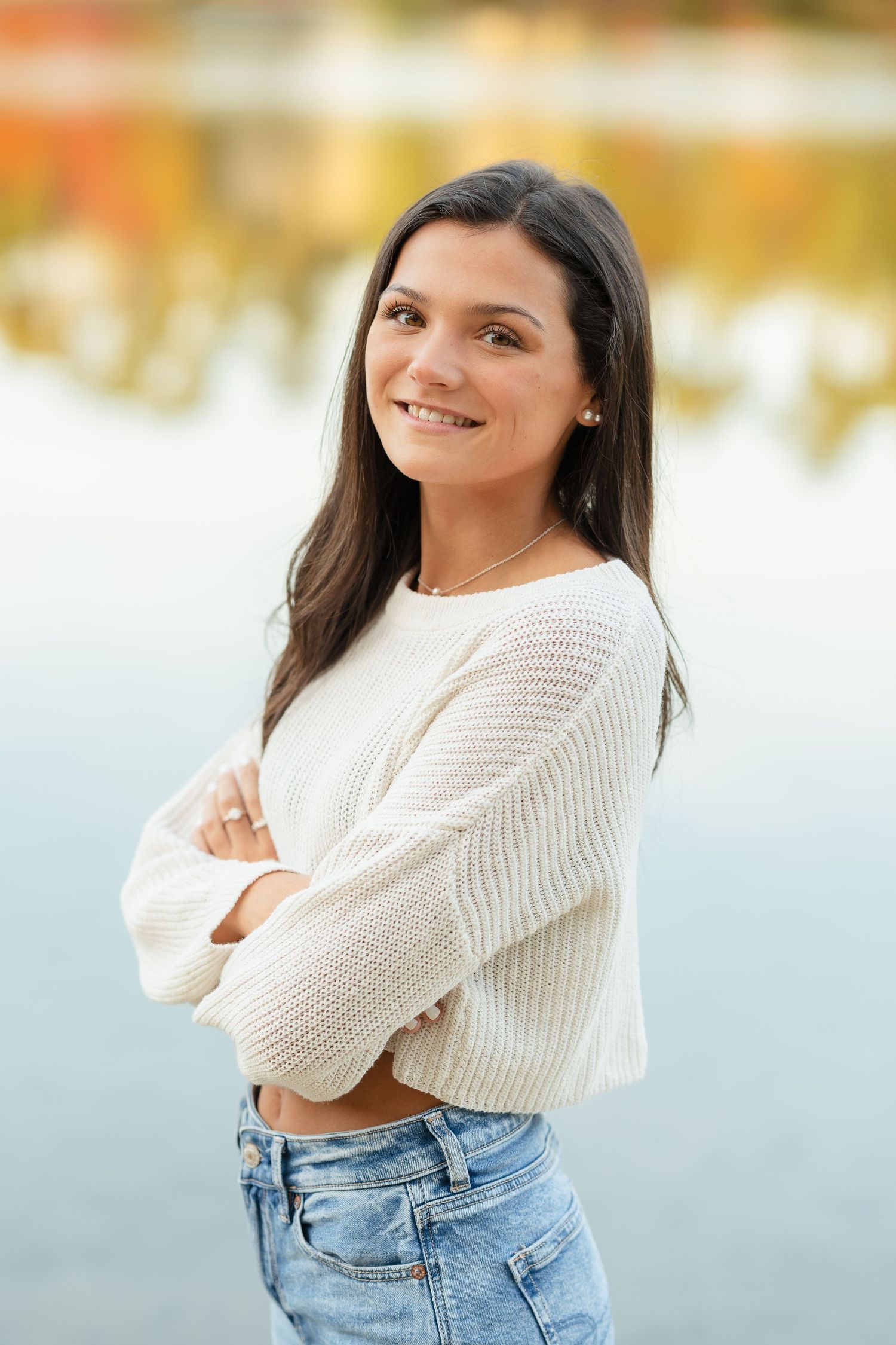 Autumn lakeside portrait in casual white sweater and jeans.