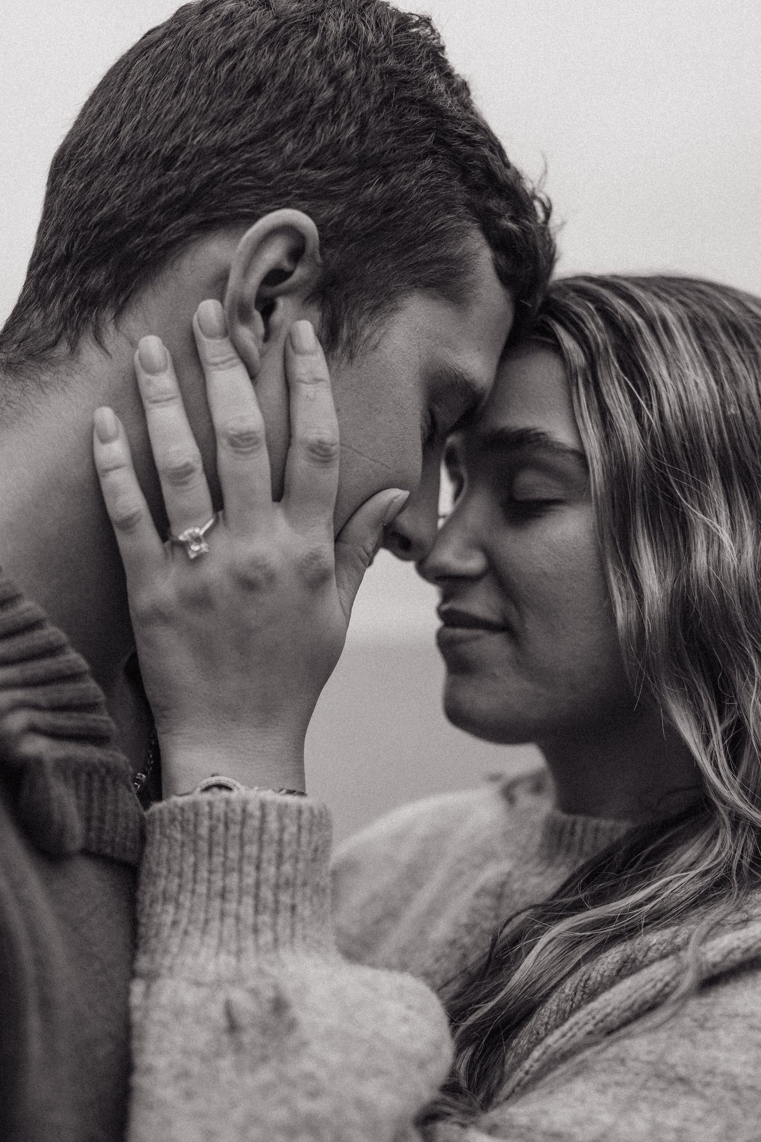 An intimate black and white portrait of a couple sharing a close romantic moment.