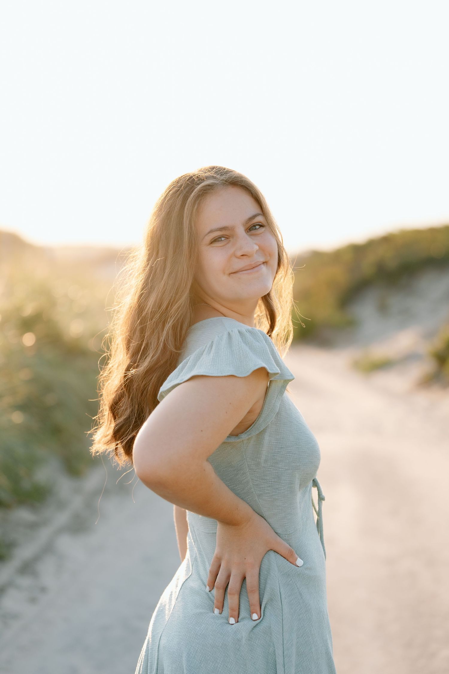 Candid portrait showing joyful expression while wearing a light blue dress outdoors.