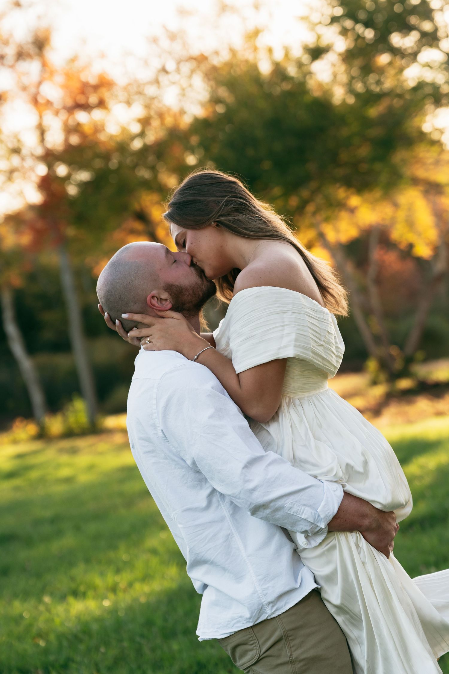 A romantic embrace captured in a sun-drenched field during golden hour.