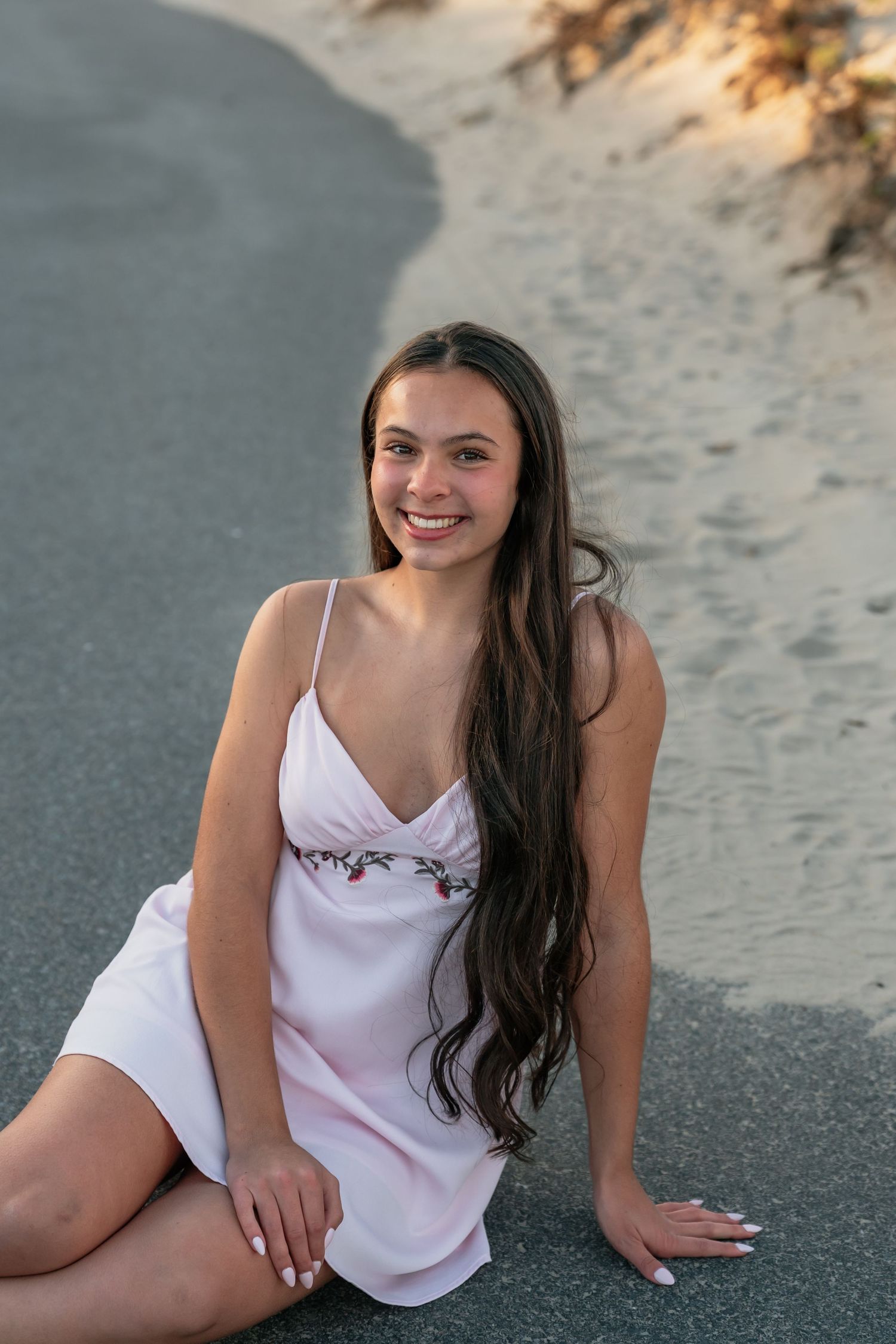 Person in white top posing on sandy ground during golden hour photoshoot.