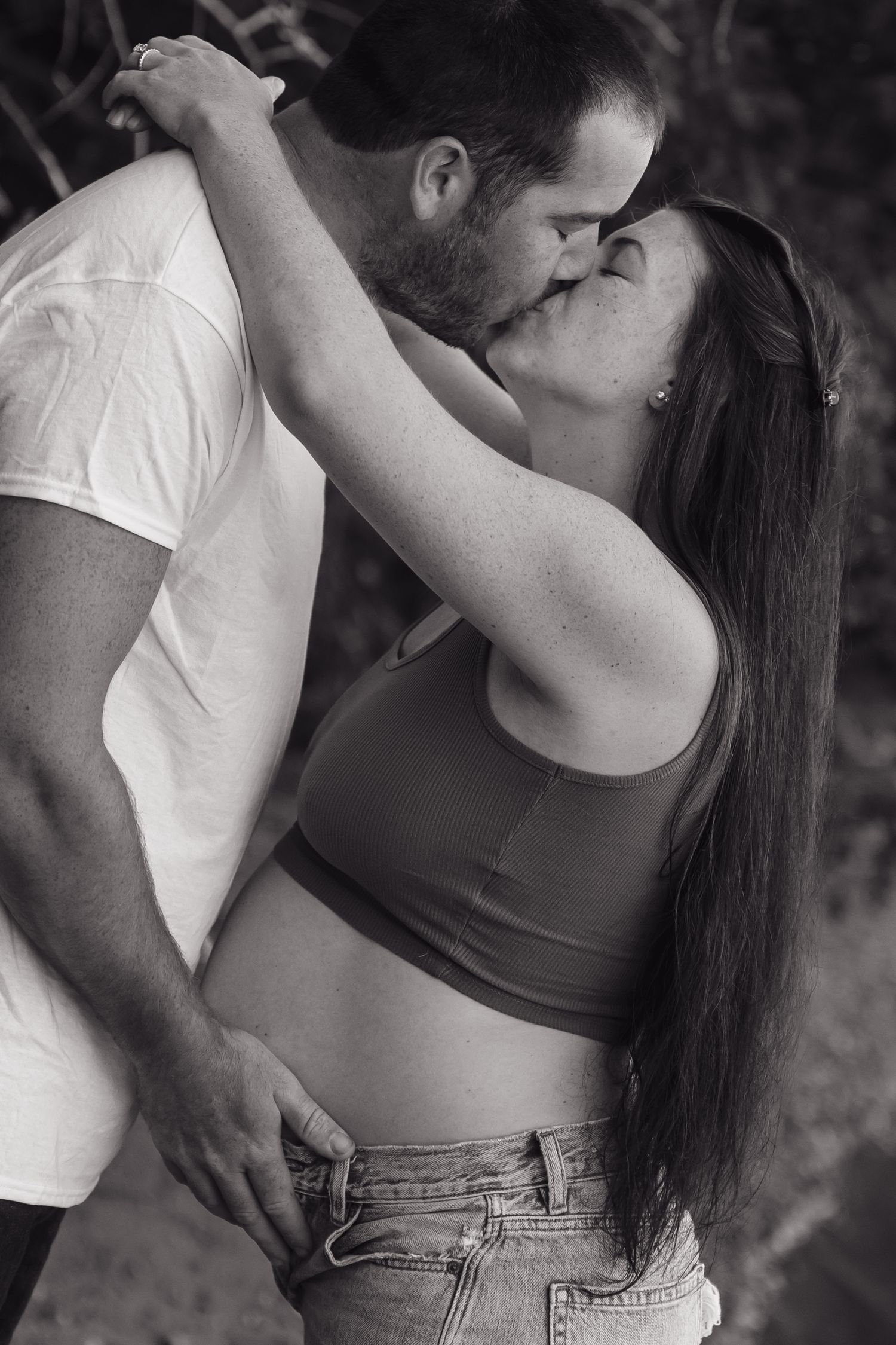 An intimate black and white portrait of a couple embracing outdoors.