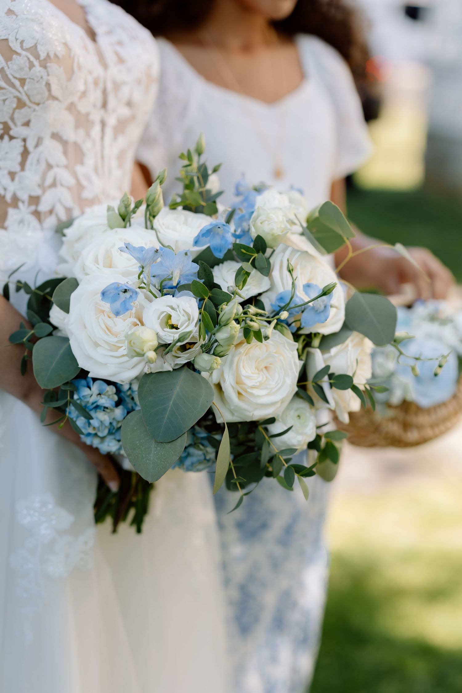 Wedding bouquets featuring white roses, blue flowers, and eucalyptus greenery.