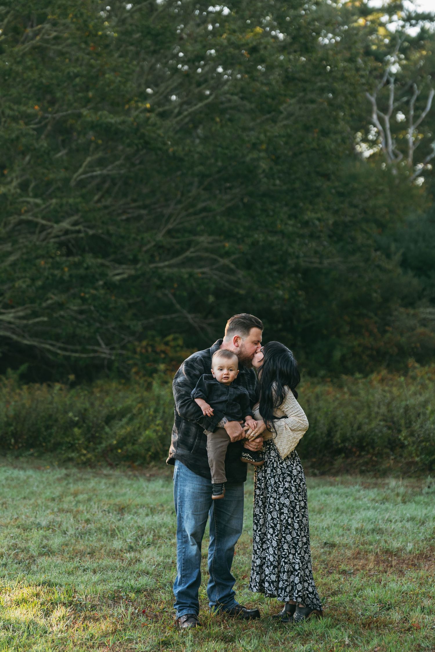 Family enjoying playful moments together on a grassy hill during autumn.