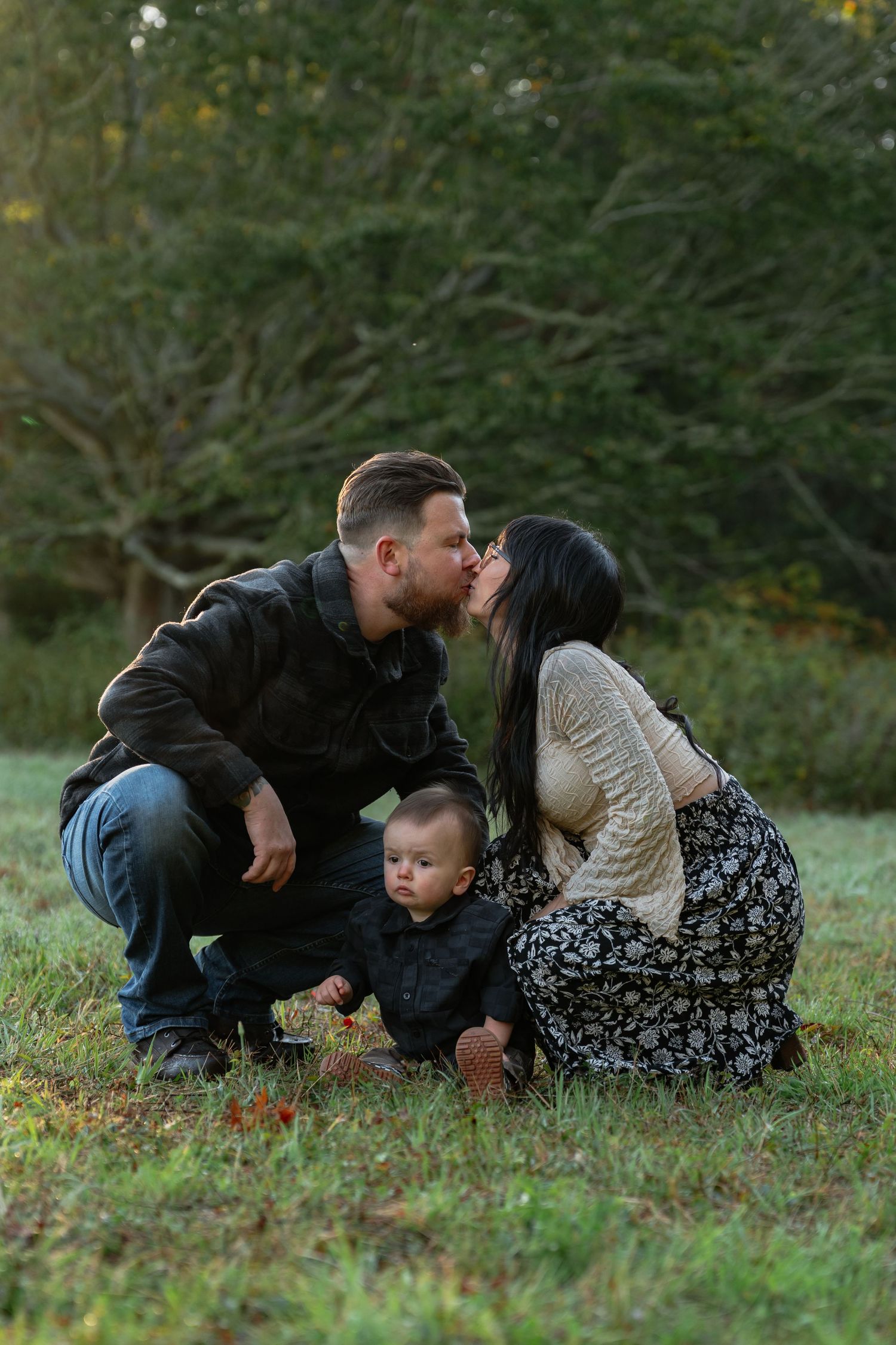 Family lying together on grass having intimate moment during fall photoshoot.