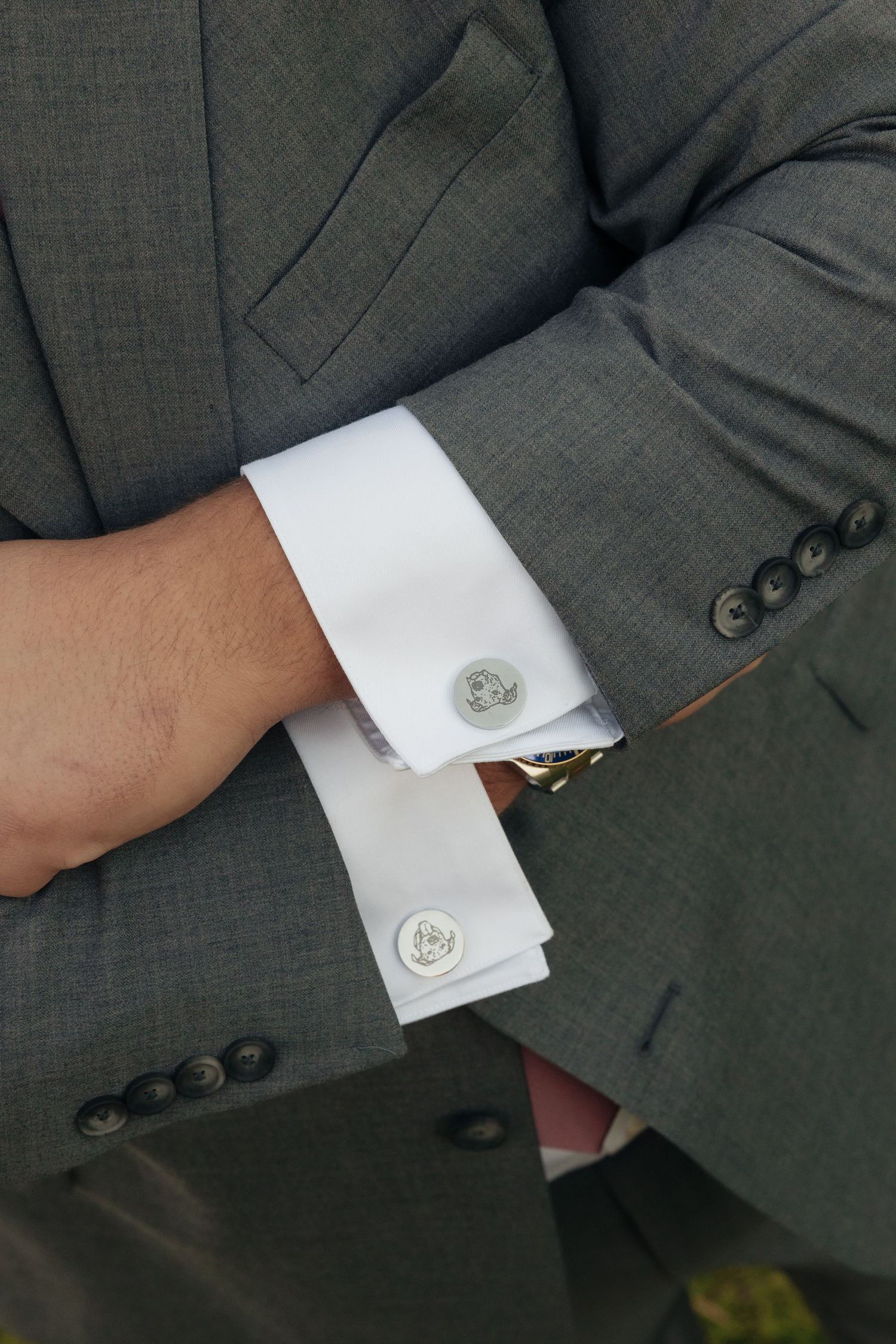 Close-up details of gray suit sleeve with white cuff and cufflink.