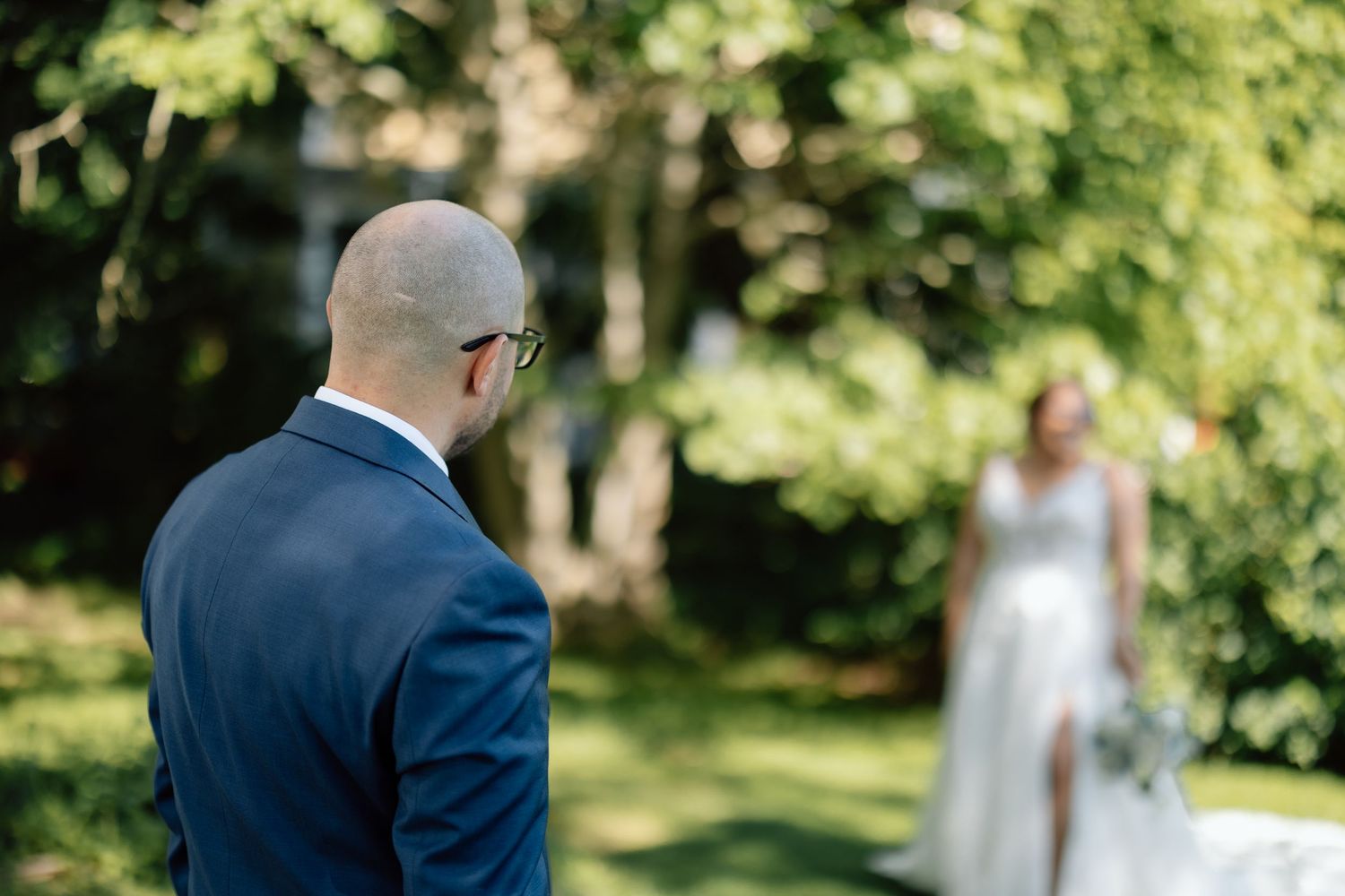 A wedding first look moment captured in a lush green garden setting.
