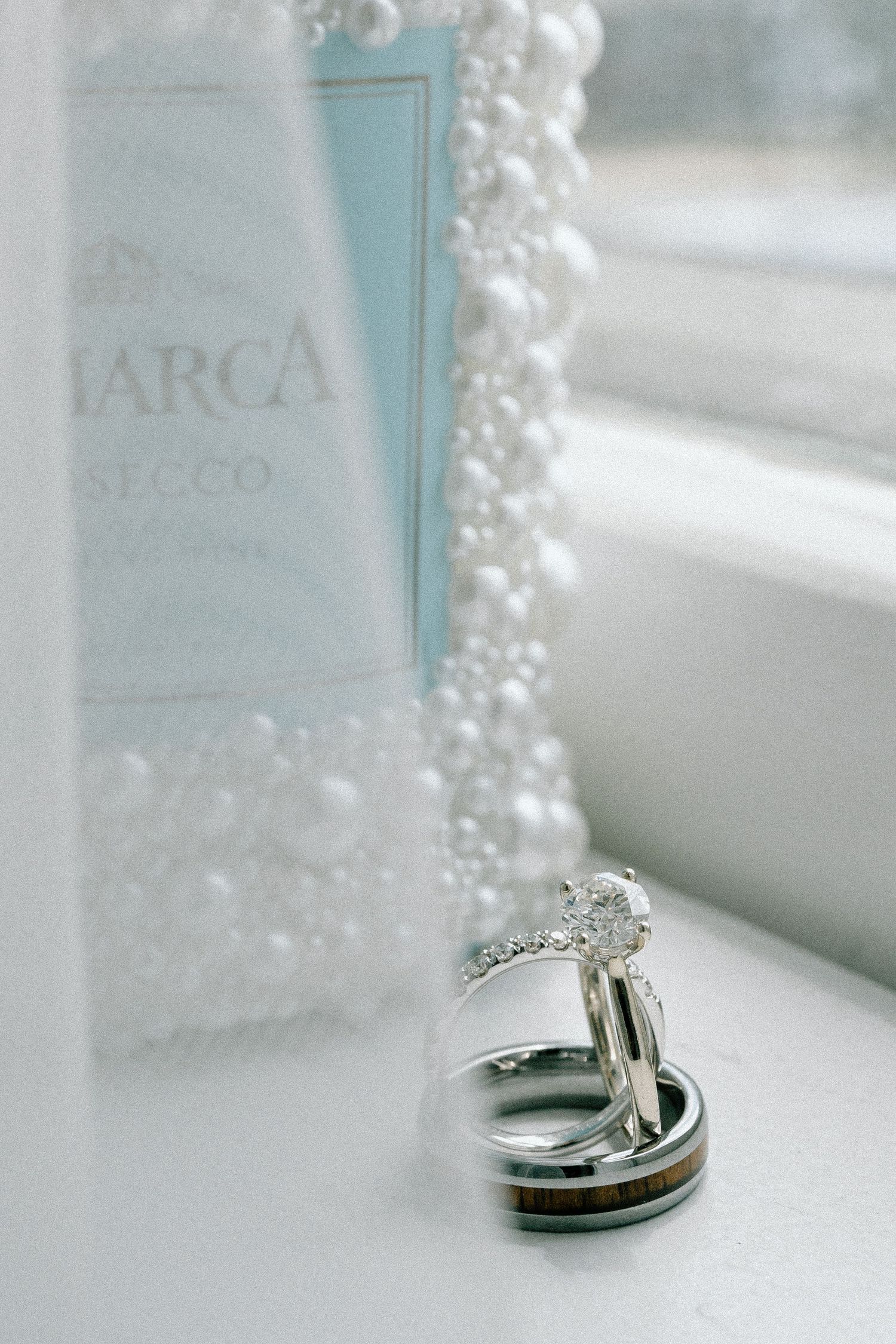 Wedding rings displayed with delicate pearl details in soft lighting.