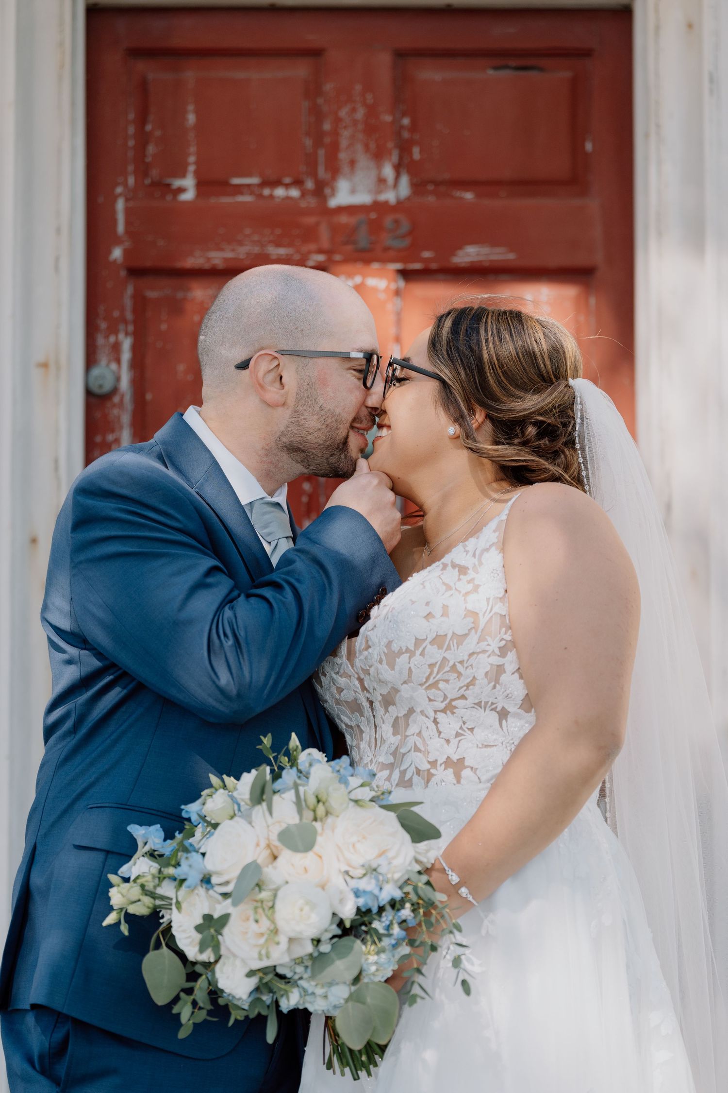 A romantic wedding moment captured in front of a weathered red door.