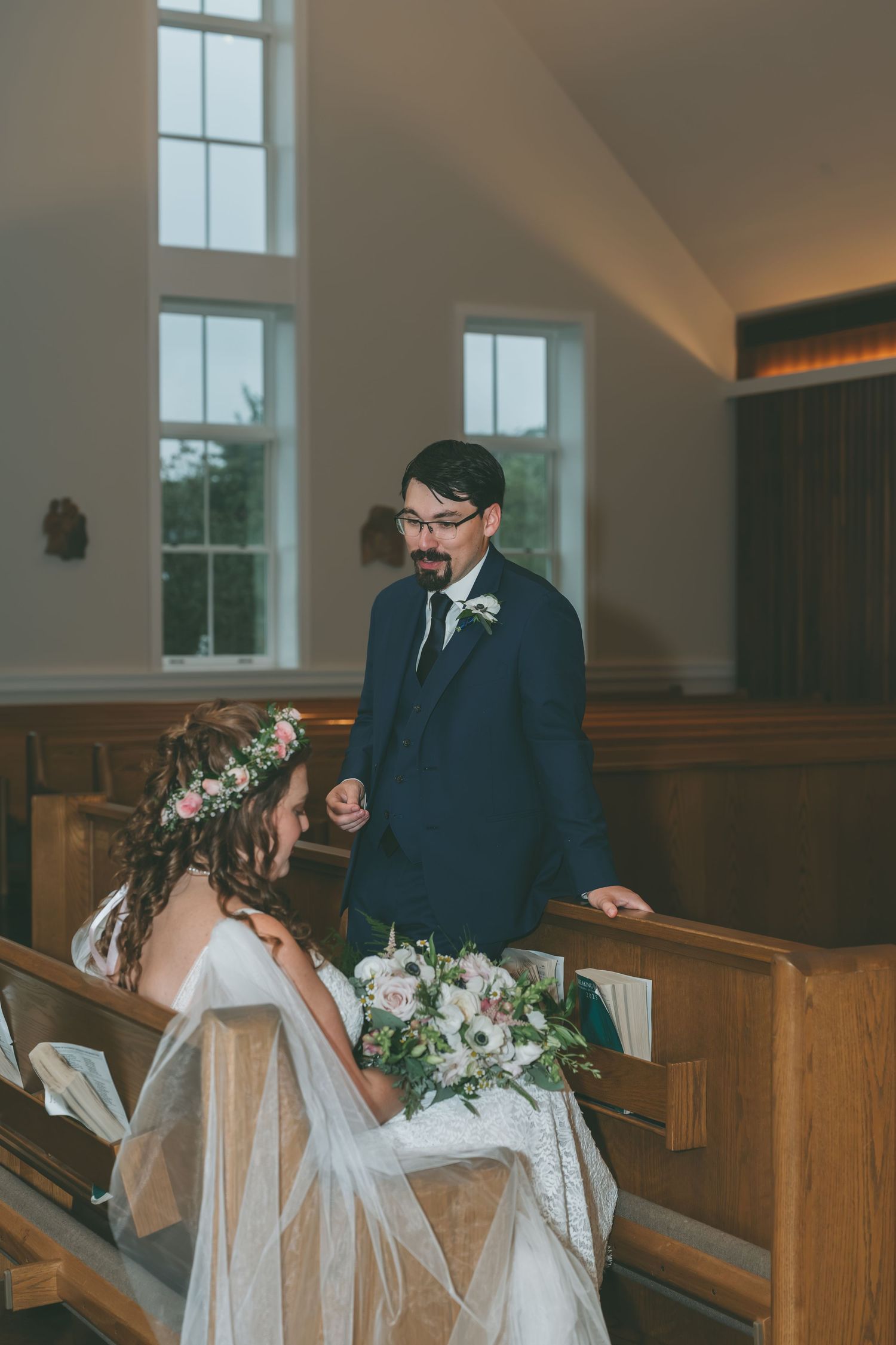 A wedding couple shares a joyful moment during their ceremony in a sunlit church.