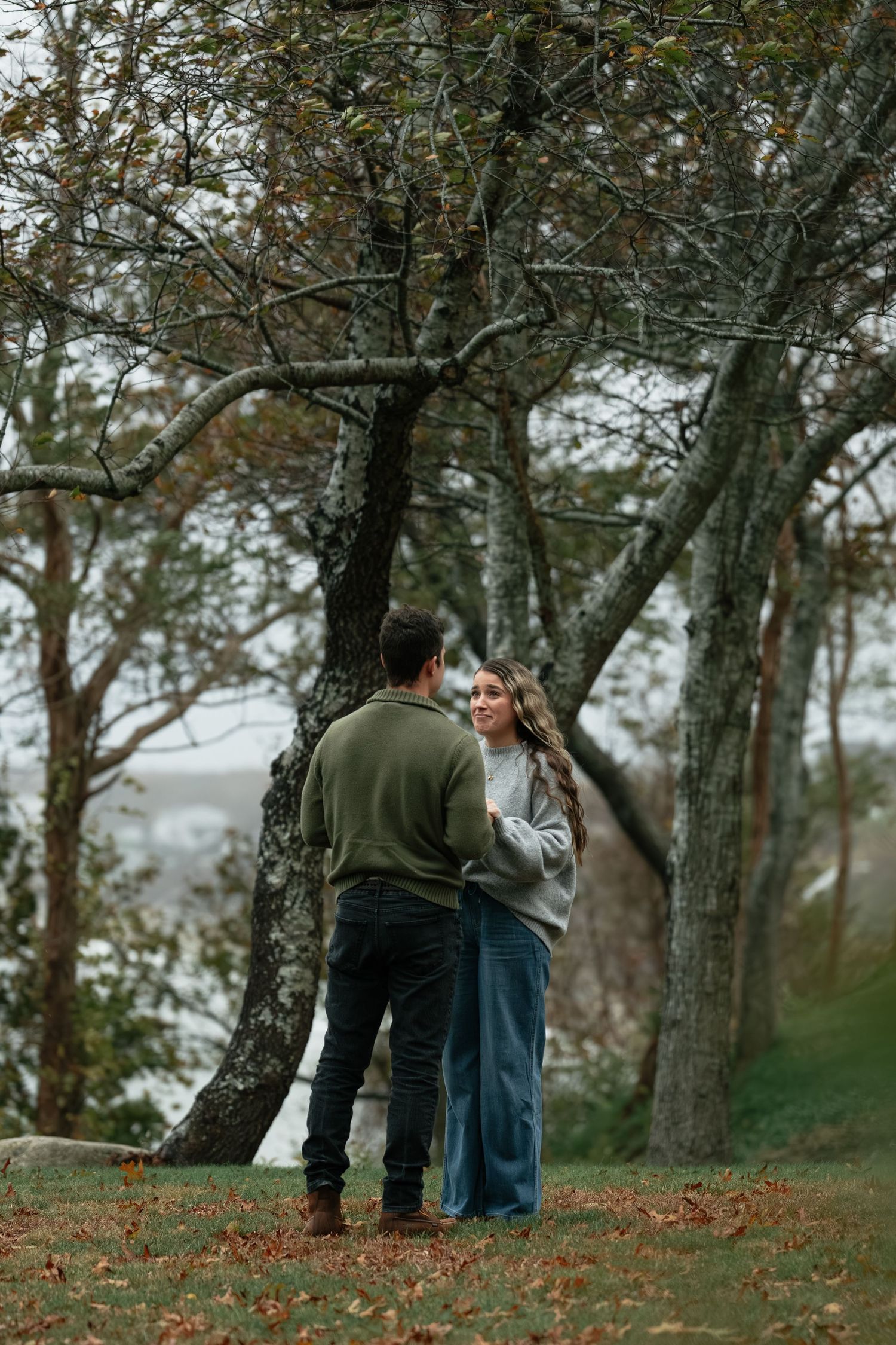 Autumn outdoor scene with people standing among bare trees on hillside.