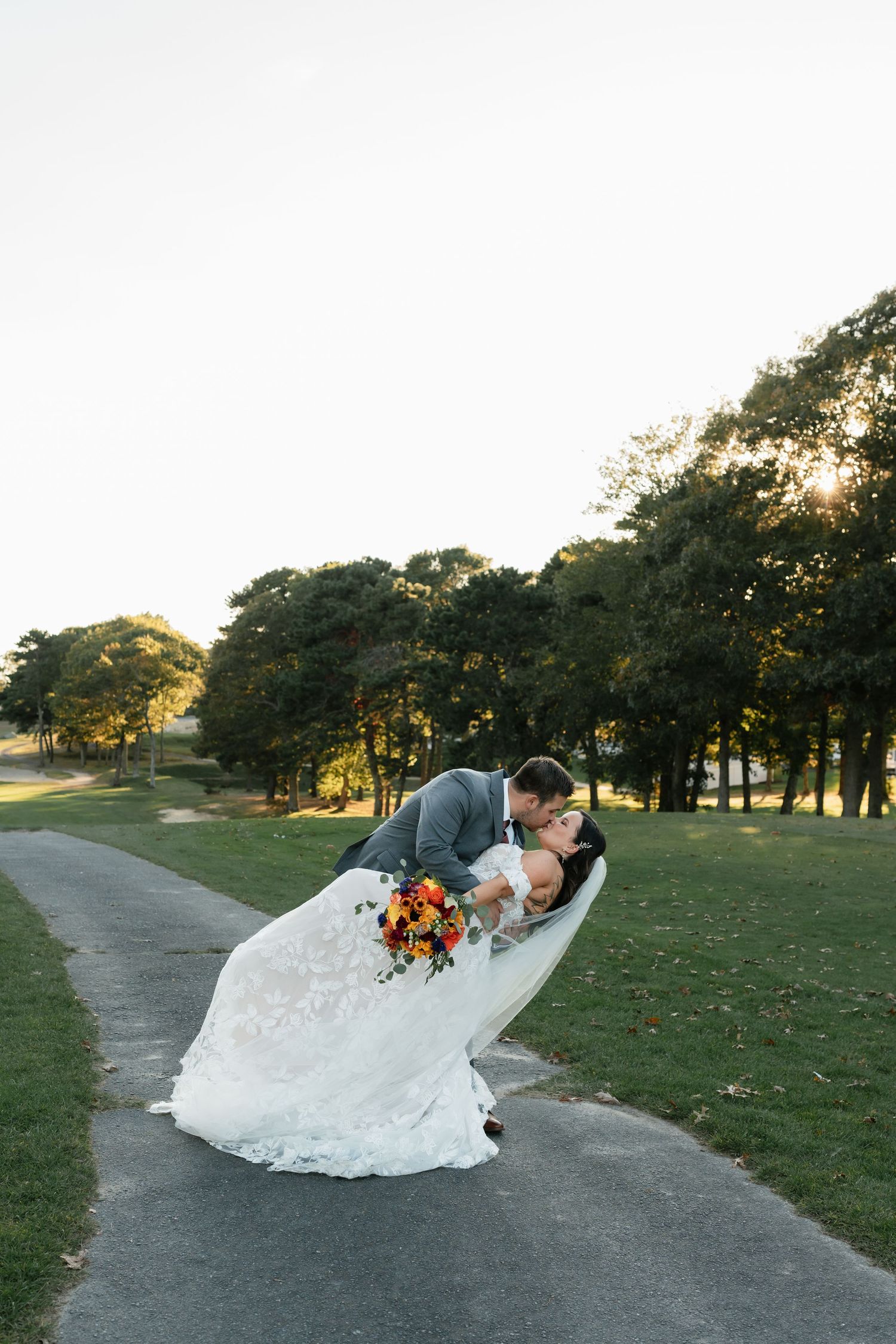 Wedding couple poses dramatically on a path during golden hour.