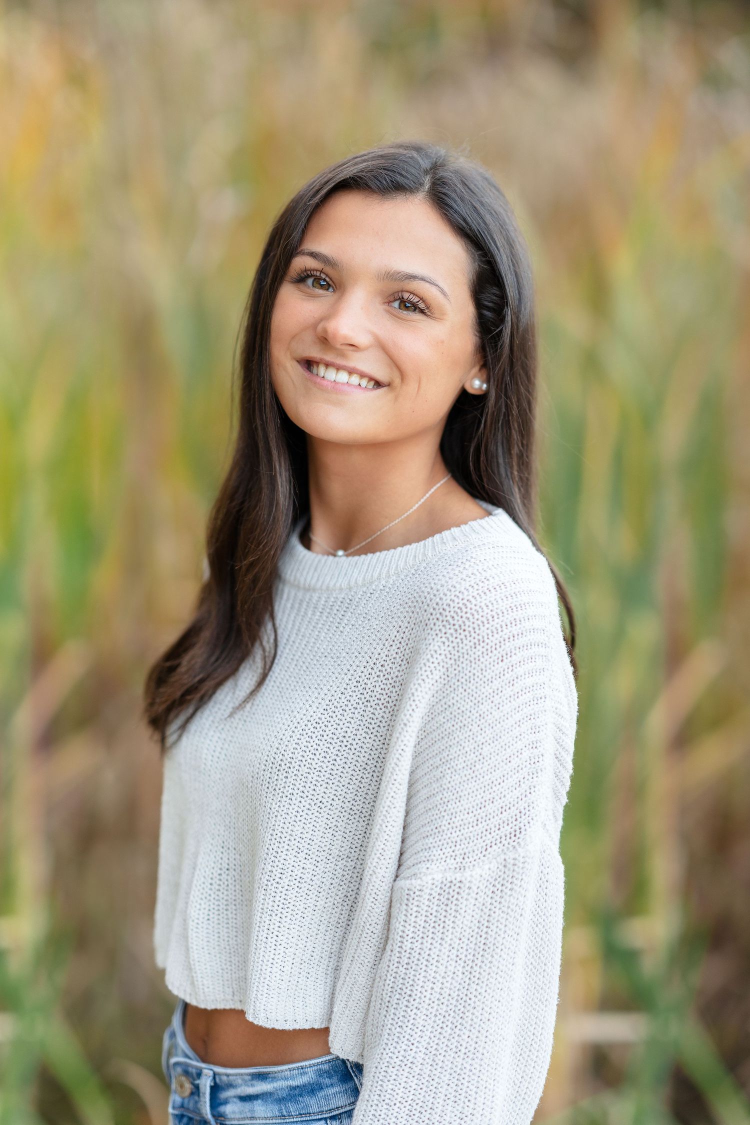 Outdoor portrait with white sweater against natural background.