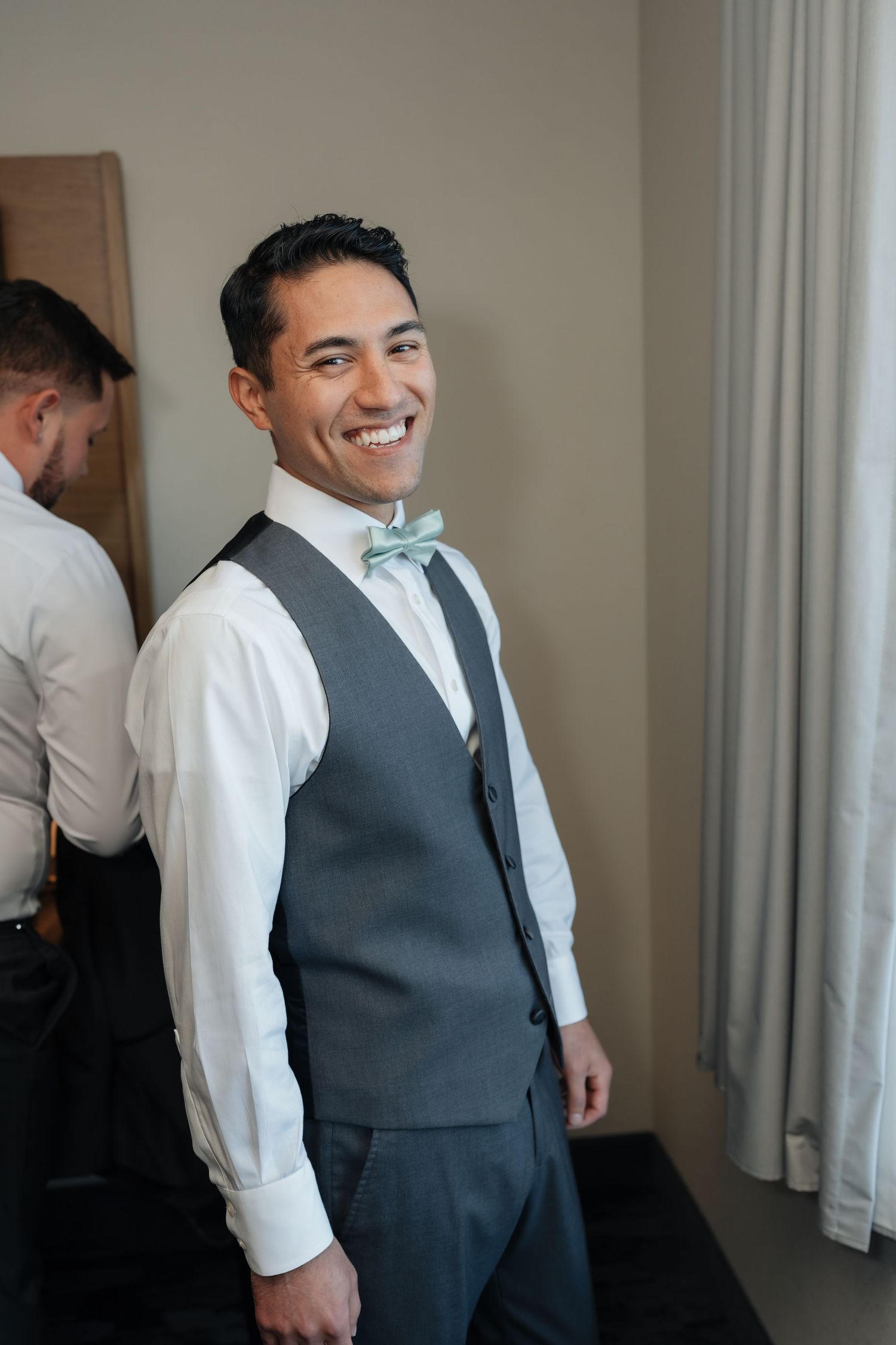 A wedding party member adjusts their mint green bowtie while getting ready.