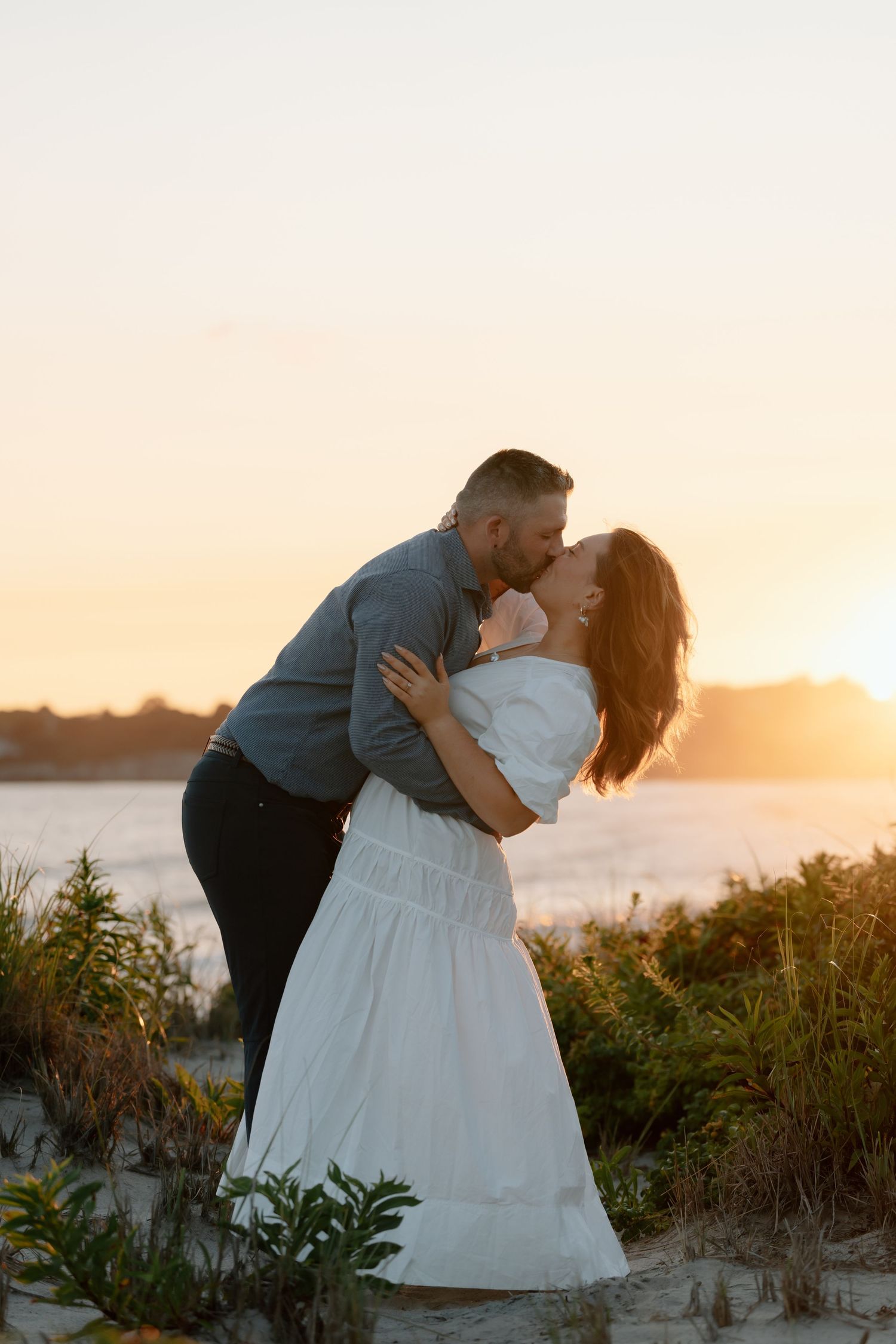 A romantic sunset embrace on a coastal sand dune.