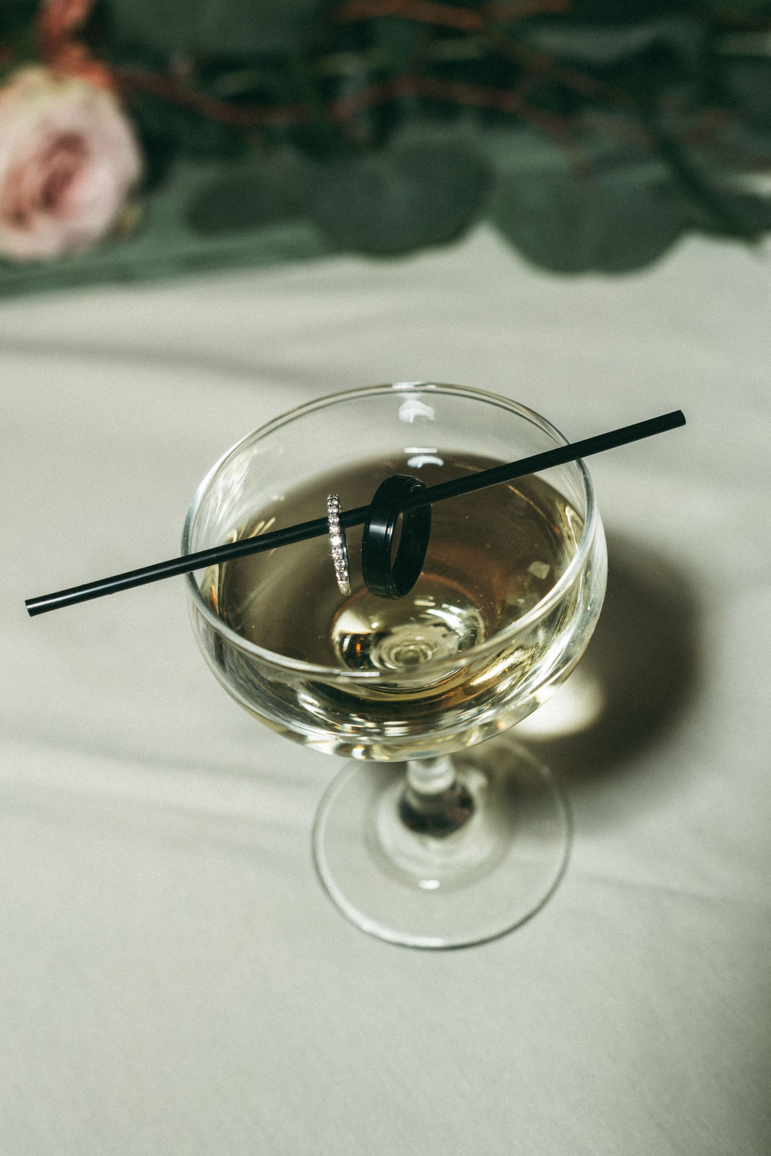 Champagne cocktail in a coupe glass with black stirrer on white tablecloth.