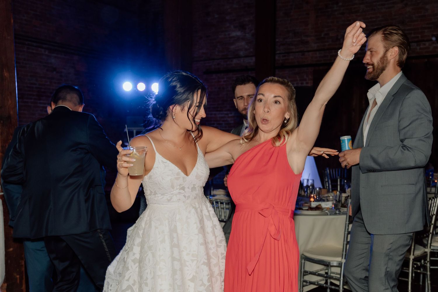 Wedding party dancing and enjoying themselves at a dimly lit reception.