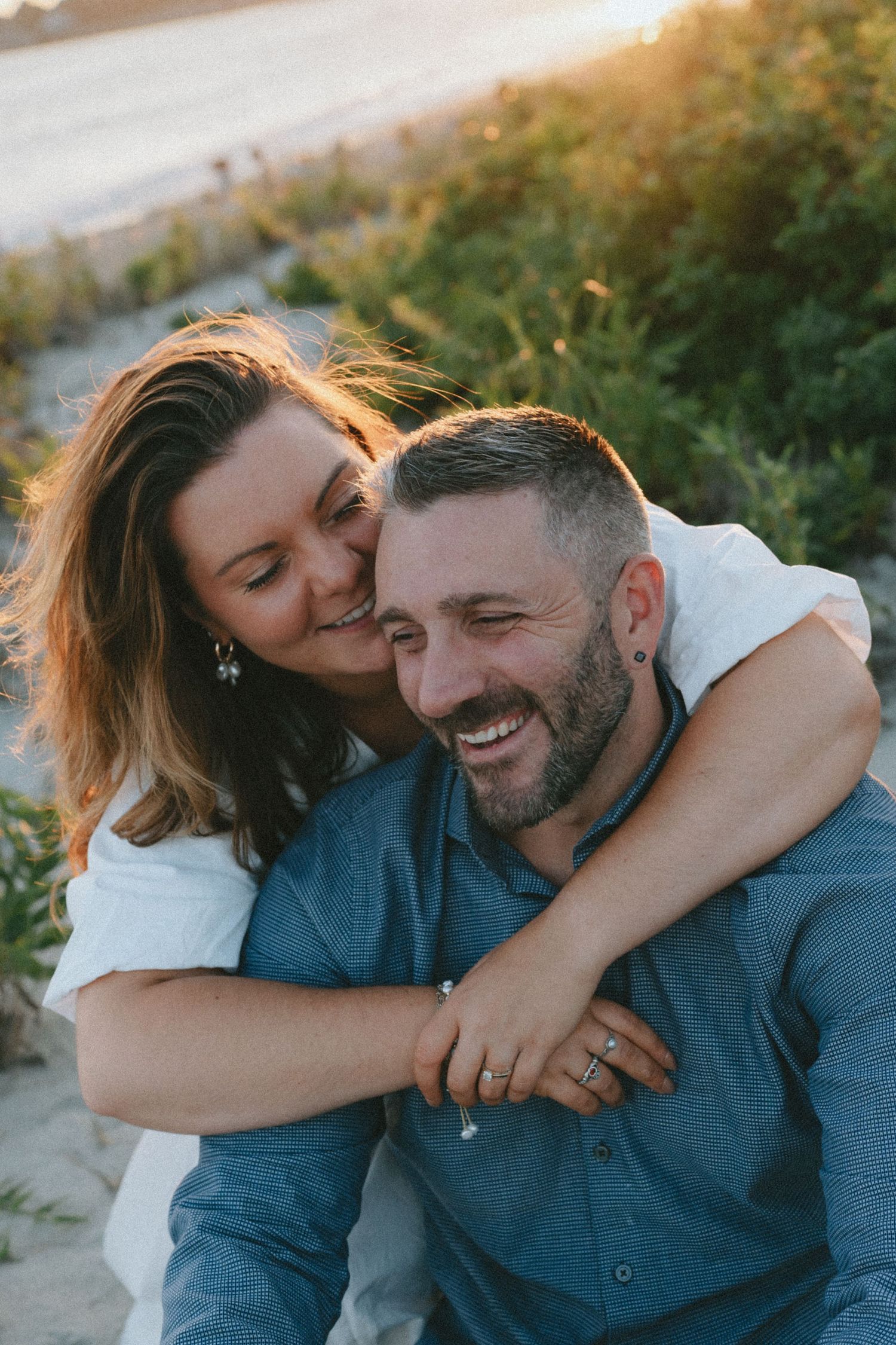 A joyful embrace captured during a beach photoshoot at sunset.