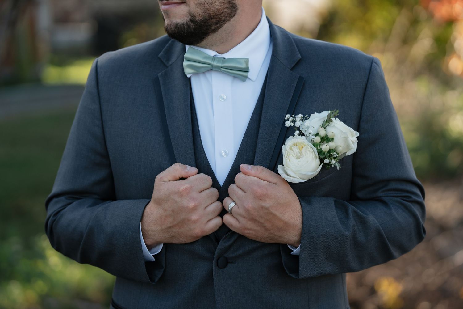 Close-up of a mint bow tie and white boutonniere on a gray wedding suit.