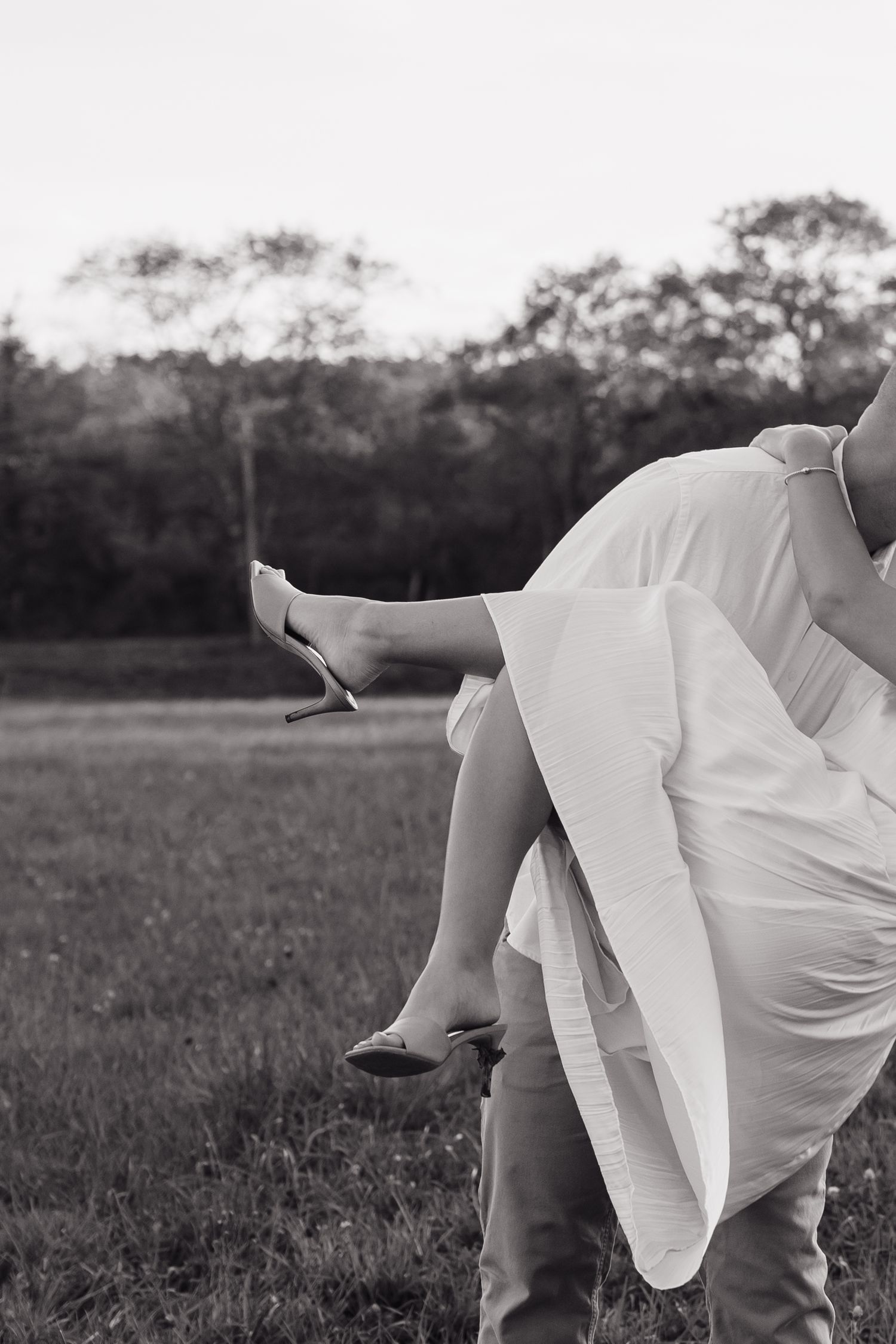 A black and white capture of a couple dancing in an open field.
