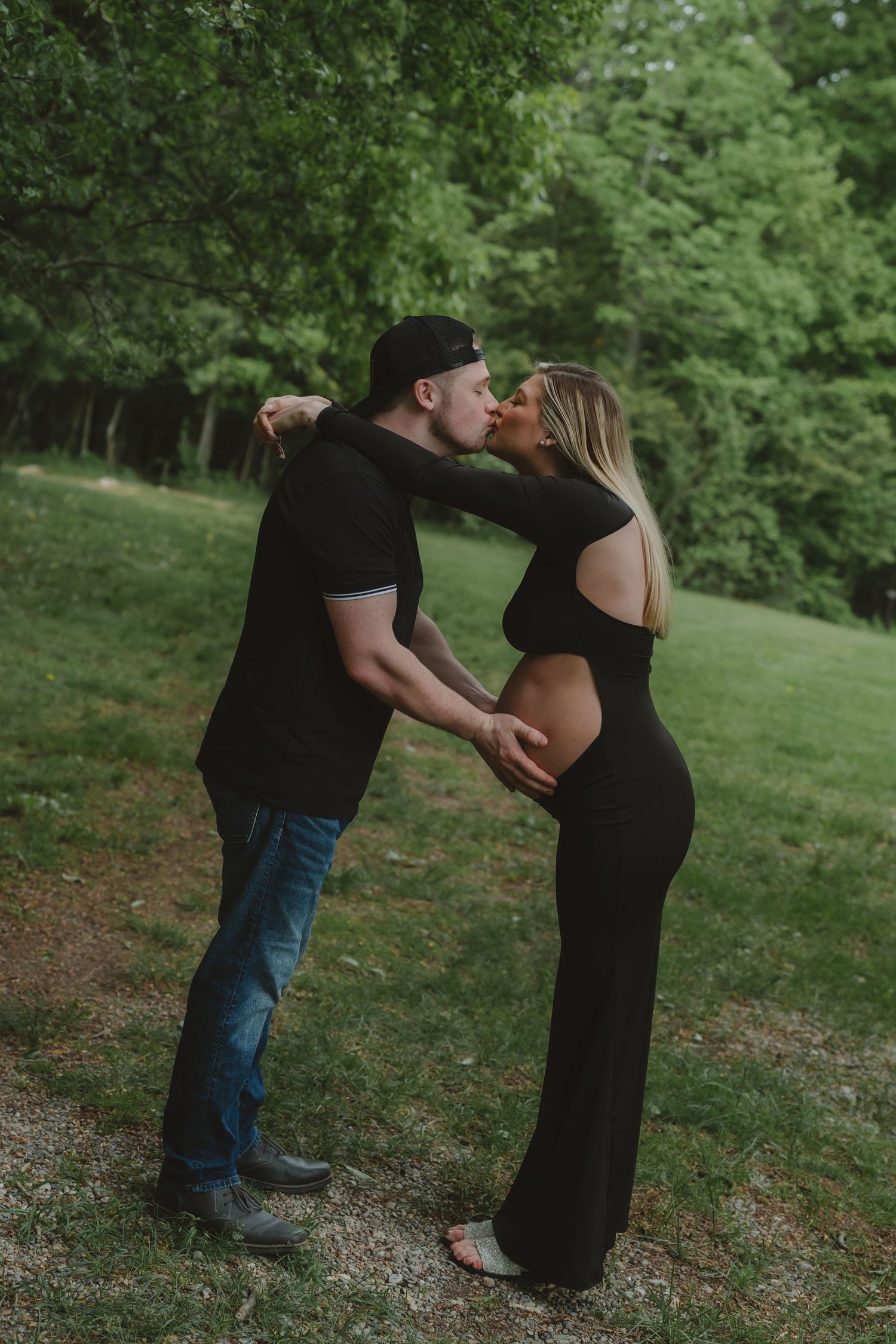 Expecting couple sharing tender moments during outdoor maternity session.