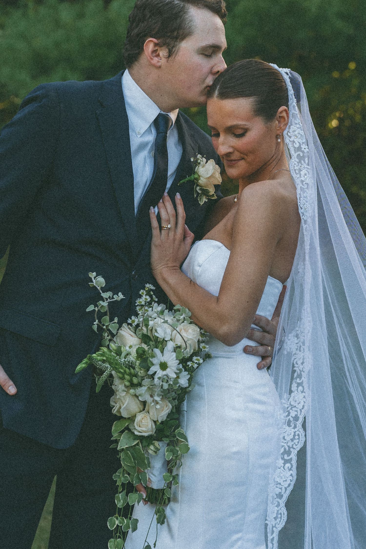 Elegant white bridal bouquet with cascading flowers and lace veil details.