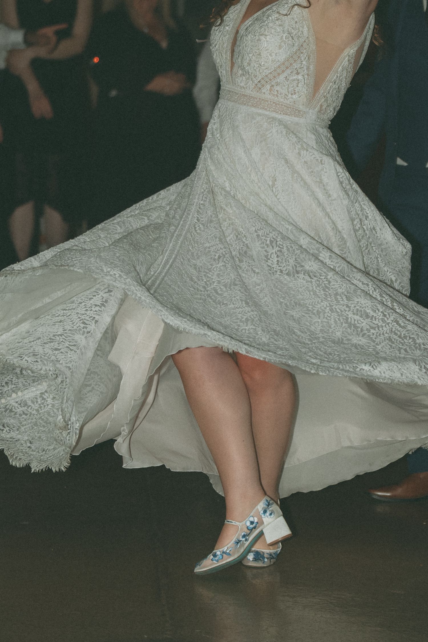 Close-up of sparkling bridal shoes and lace dress hem during a wedding dance.
