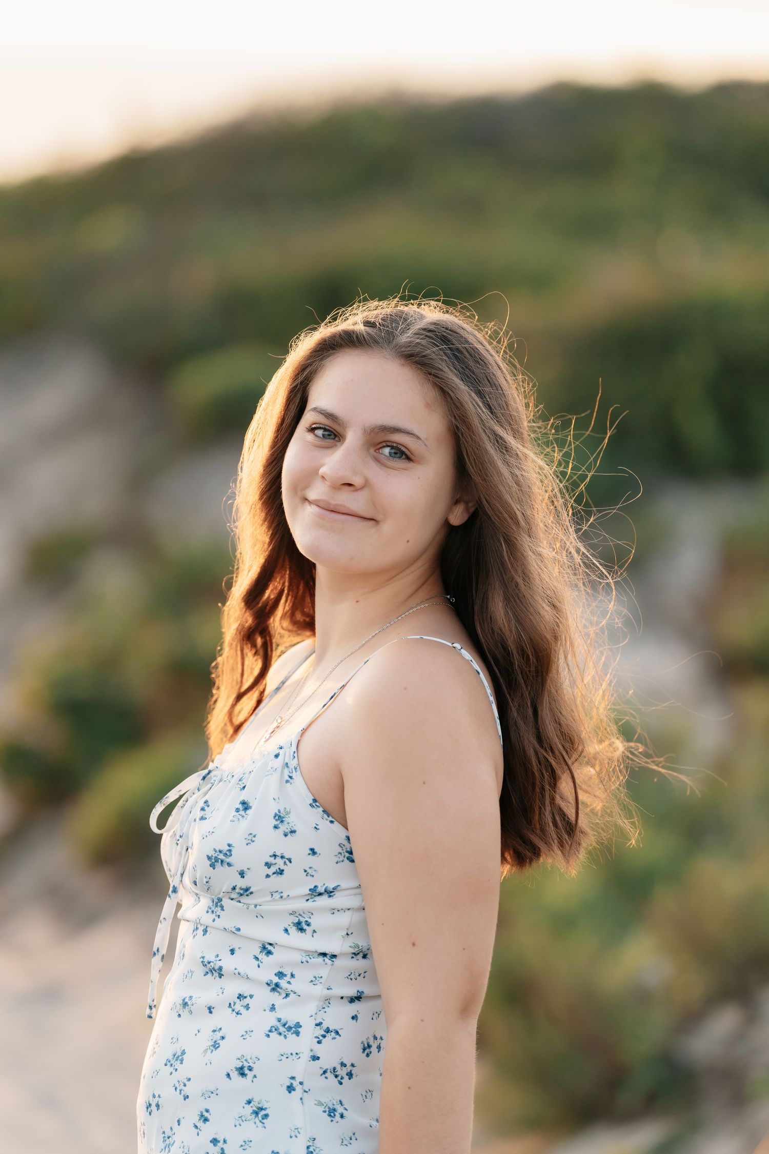 Summer portrait in a floral dress against sand dunes during golden hour.