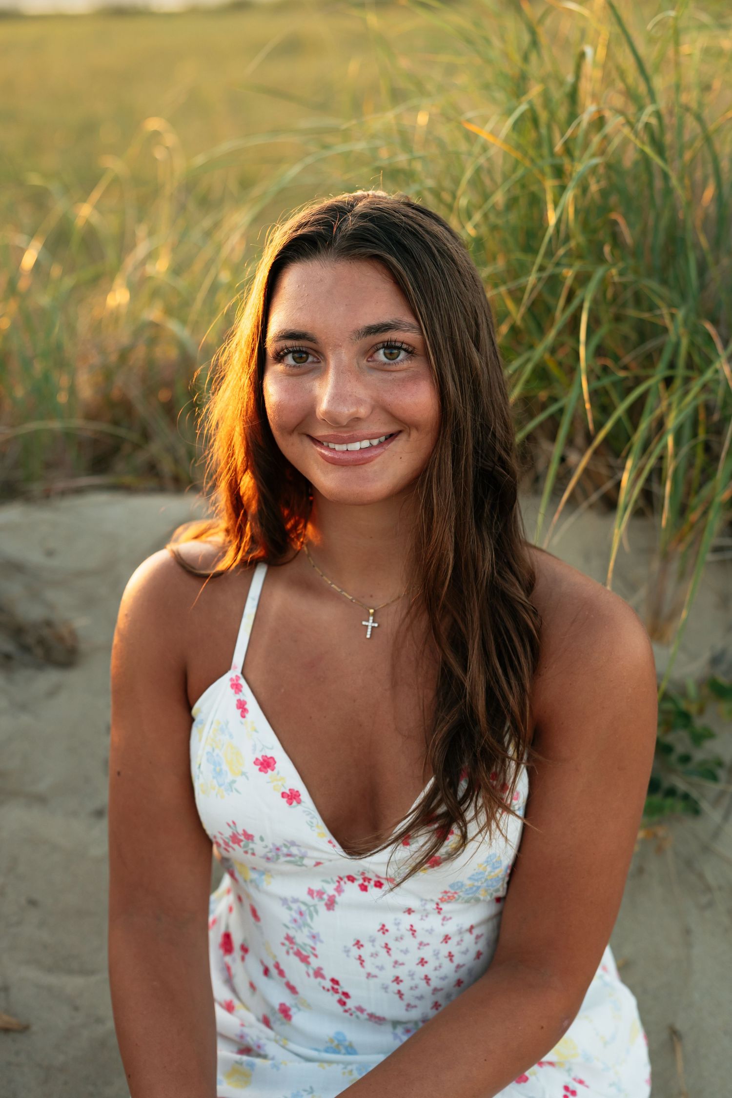 Summer portrait in white floral sundress against beach grass at golden hour.