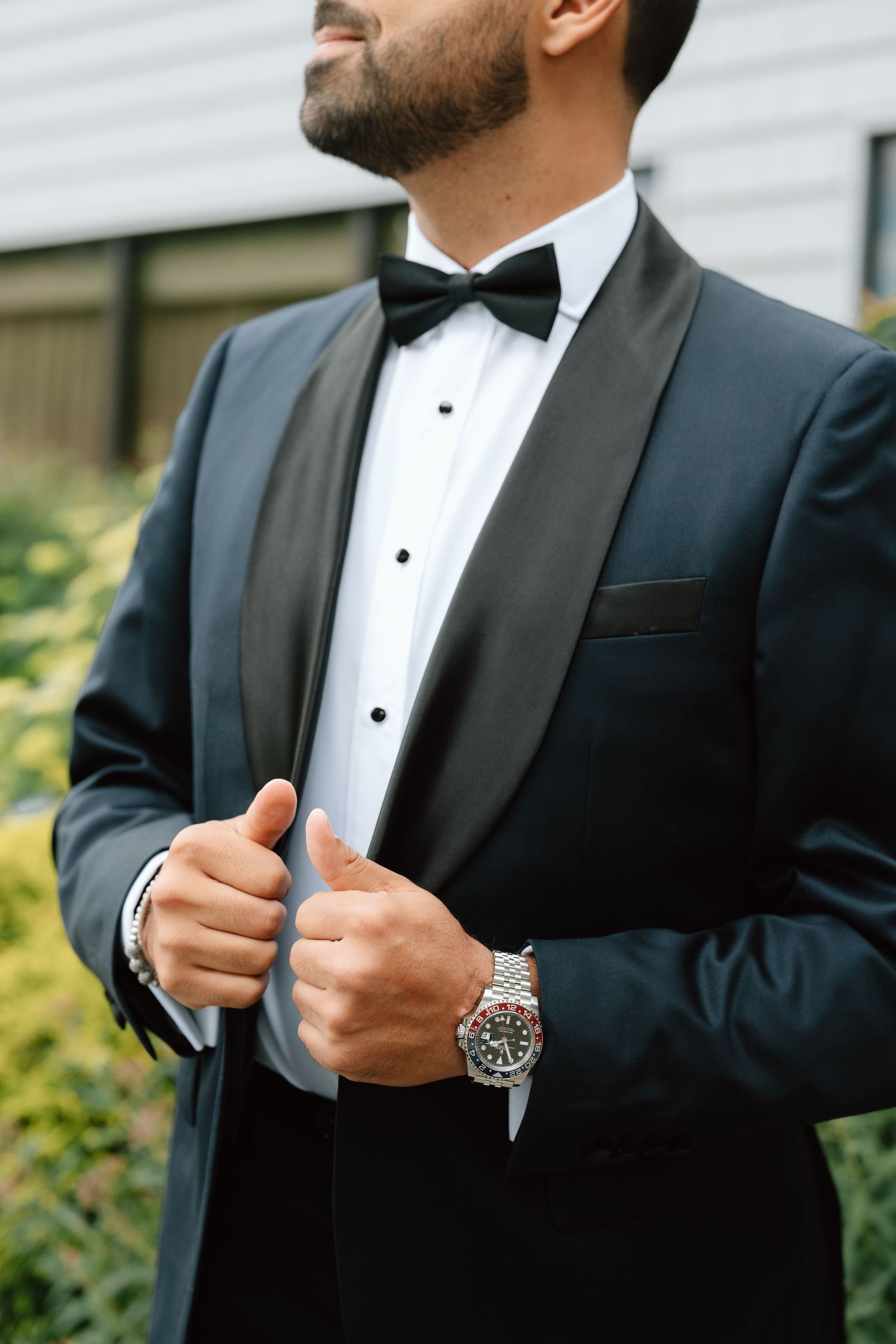 Close-up of luxury watch and bowtie detail on classic black tuxedo.