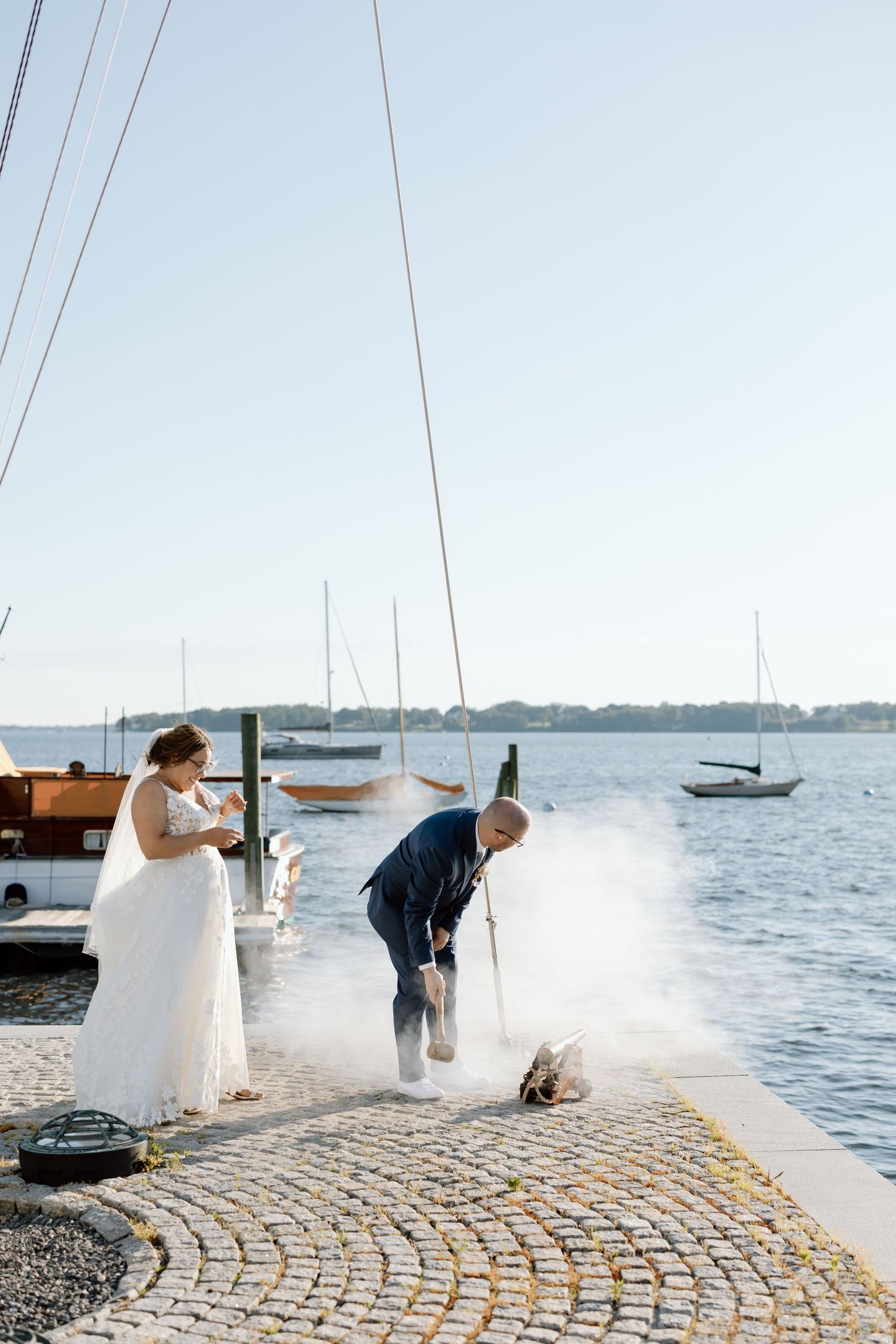 Wedding celebration on a waterfront dock with boats in the harbor.