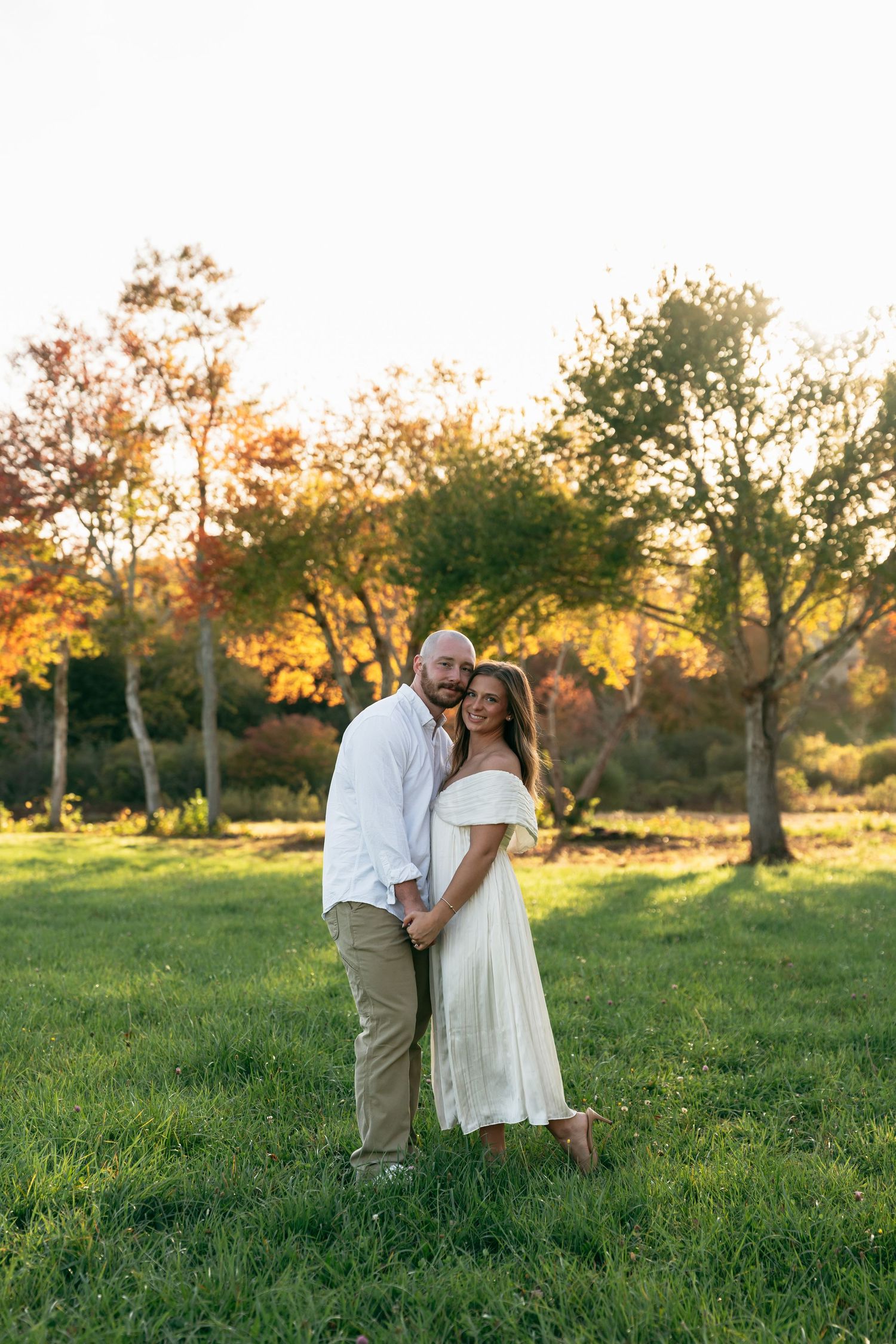 A couple shares a romantic moment in a sunlit meadow at golden hour.