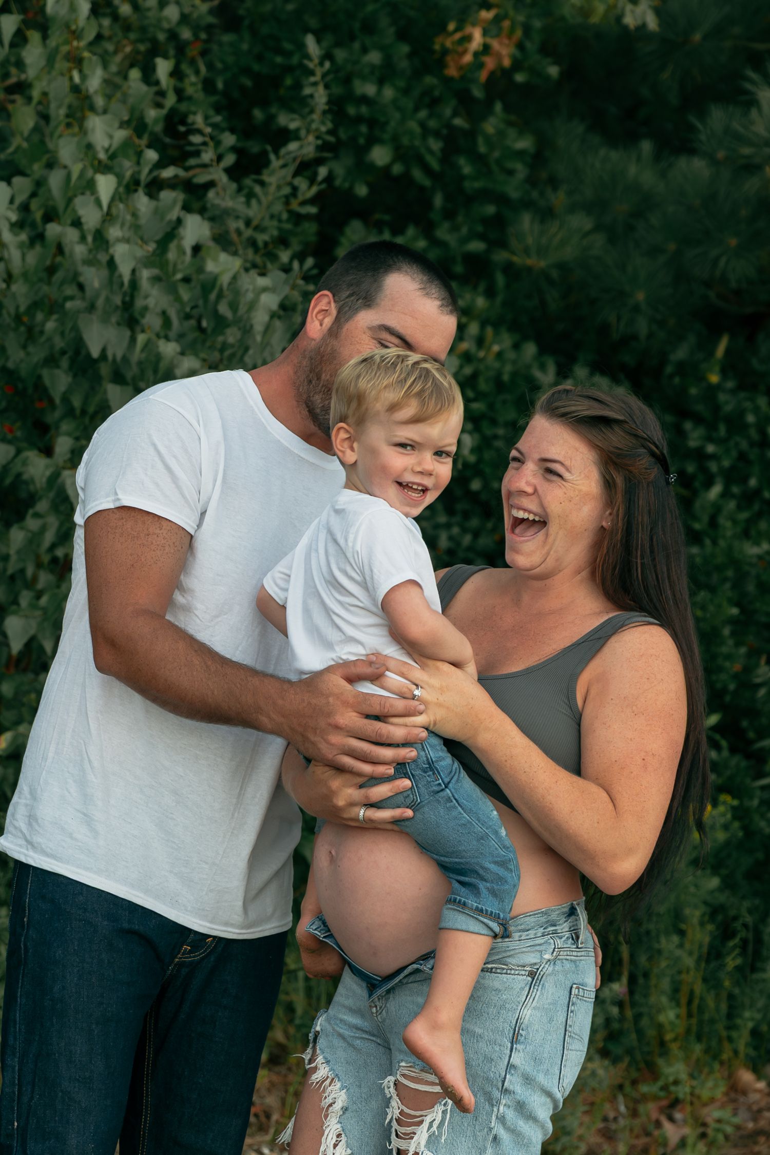 A joyful family moment outdoors with laughter and embraces against a leafy background.