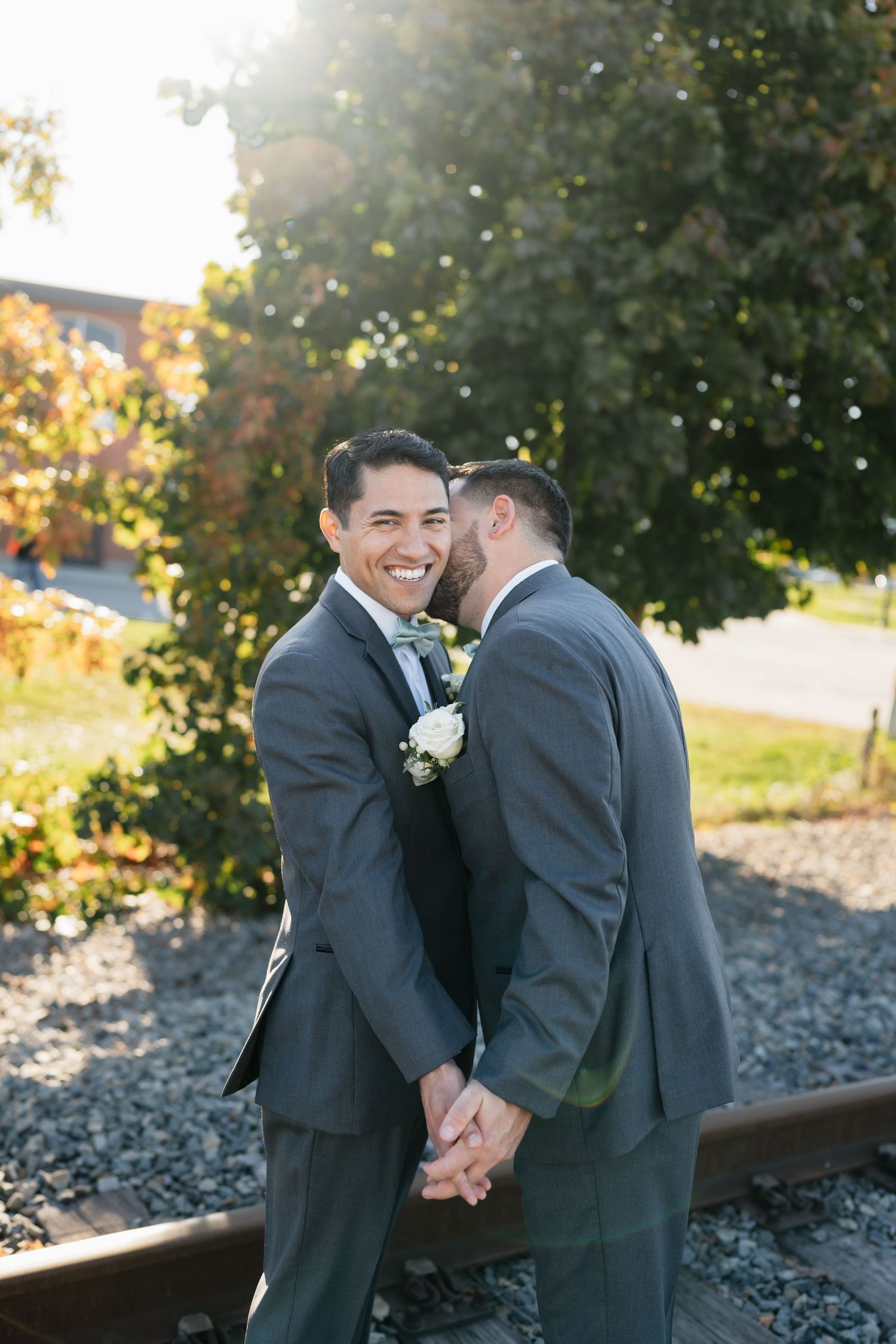 A joyful wedding moment captured outdoors with autumn trees in the background.