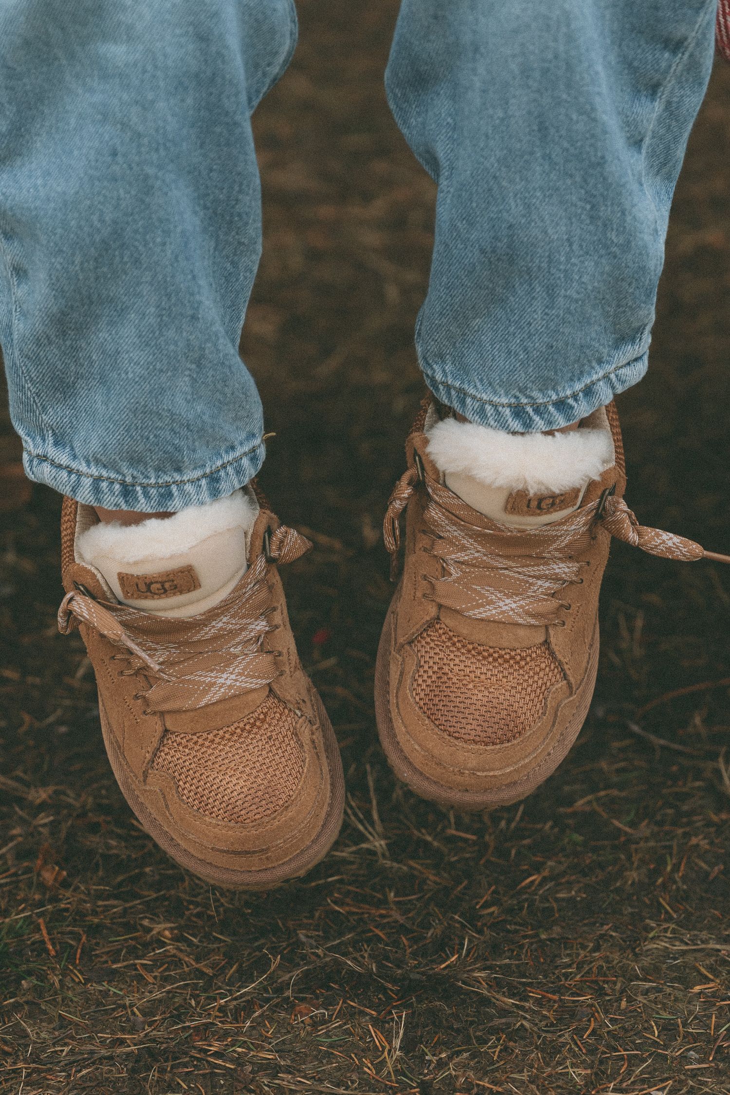 Close-up view of small brown leather boat shoes on feet wearing light blue jeans.