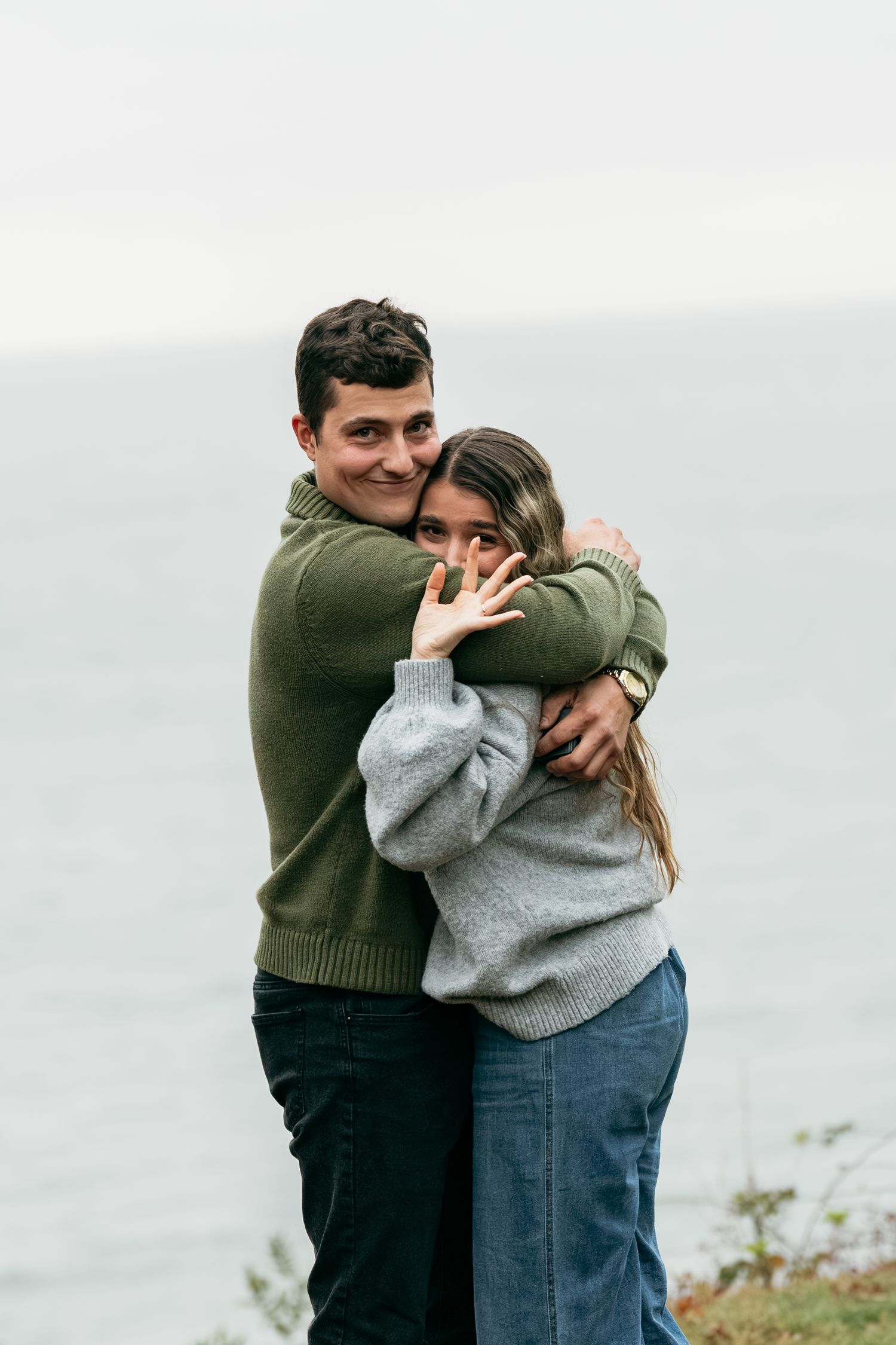 A joyful embrace captured against a misty coastal background.