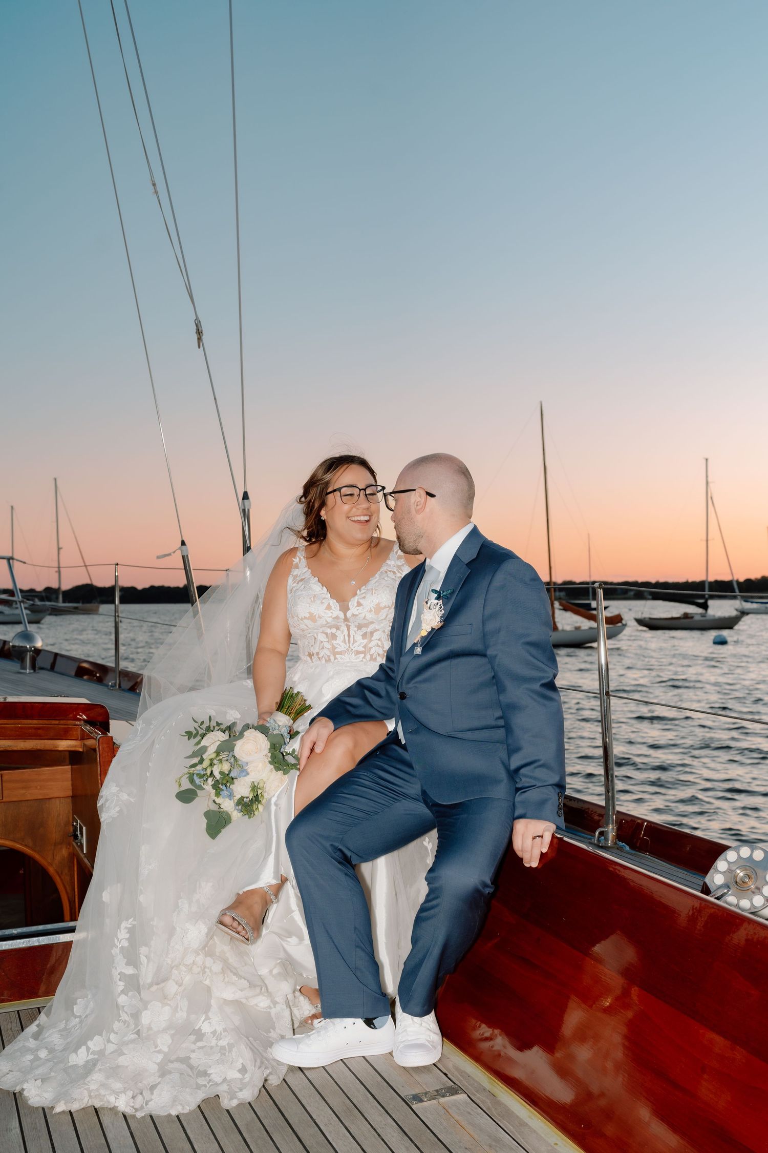 Romantic sunset wedding photos captured on a sailboat with water and boats in the background.