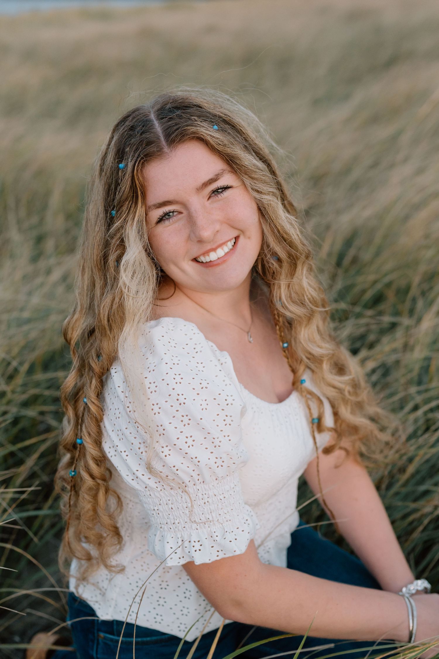 Natural outdoor portrait in white lace top surrounded by beach grass.