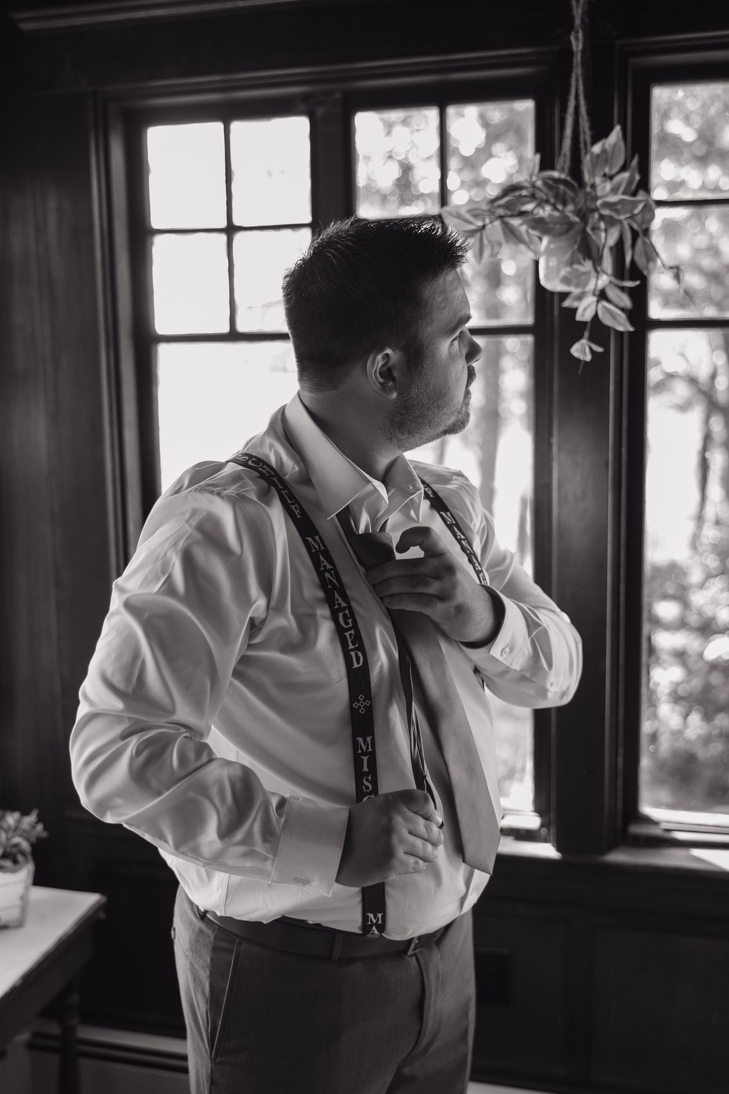 A person in formal attire preparing for an event in a room with natural lighting.