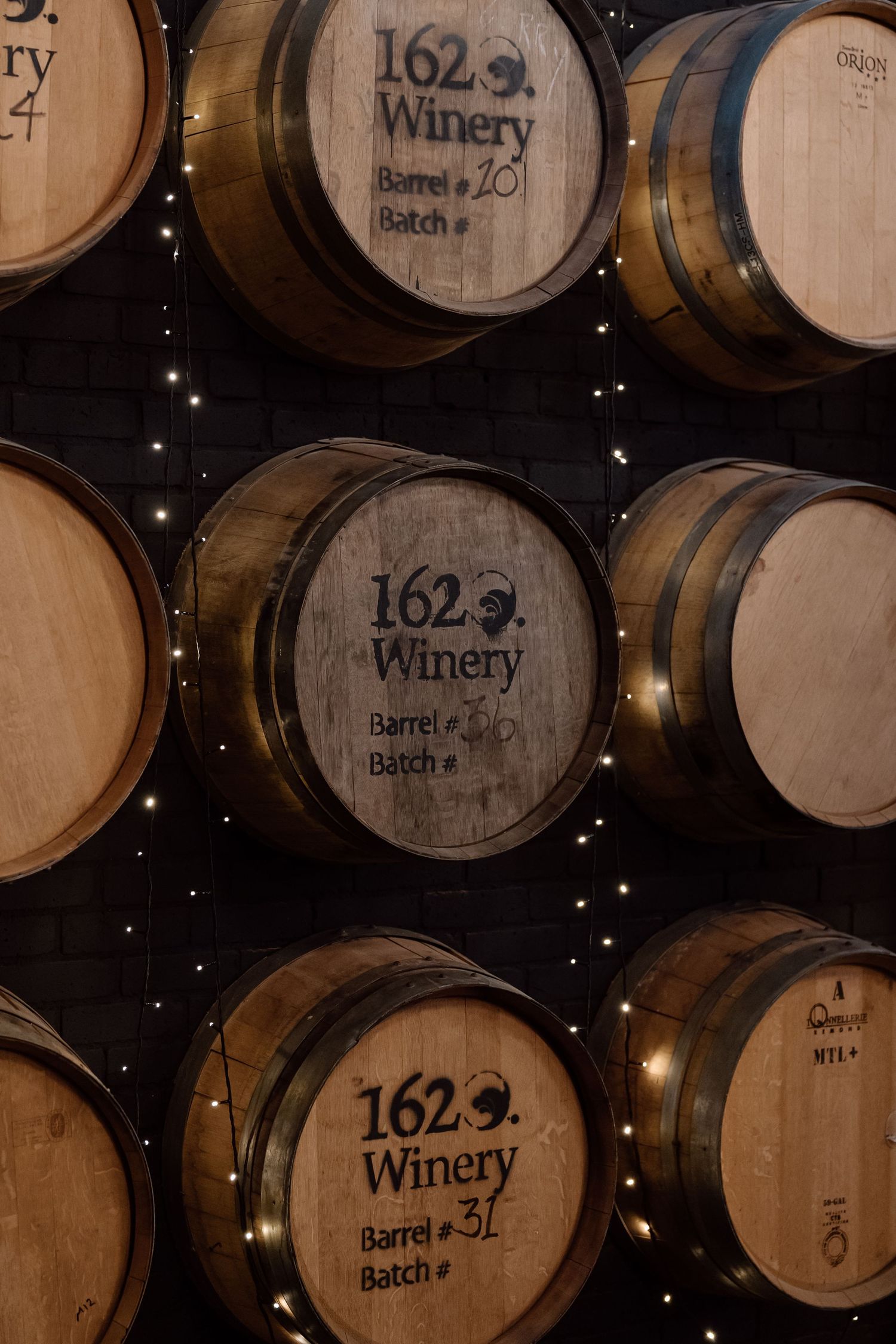 Wine barrels stacked in cellar with winery branding visible.