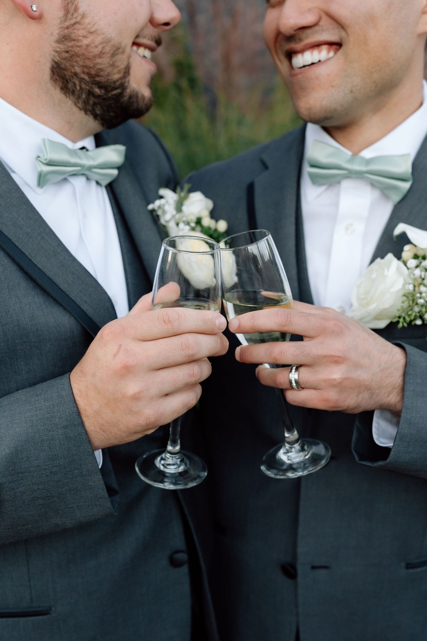 Wedding toast with champagne glasses featuring mint bow ties and white boutonnieres.