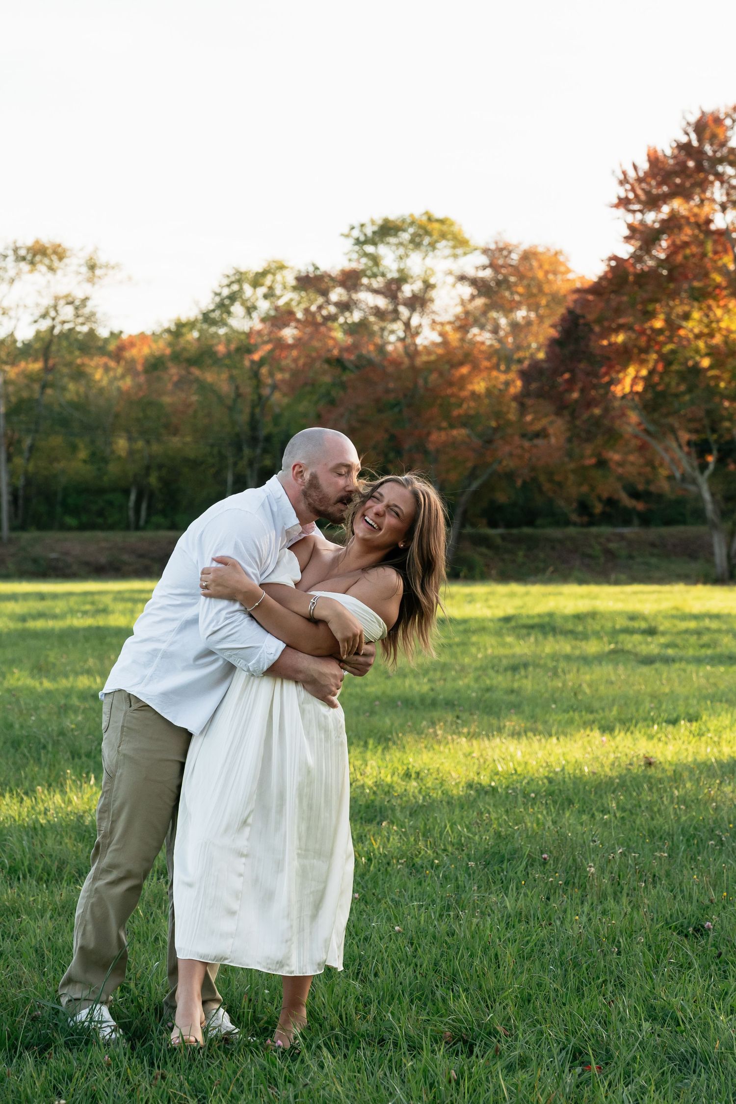 A romantic couple dances and embraces in a sunlit meadow during golden hour.