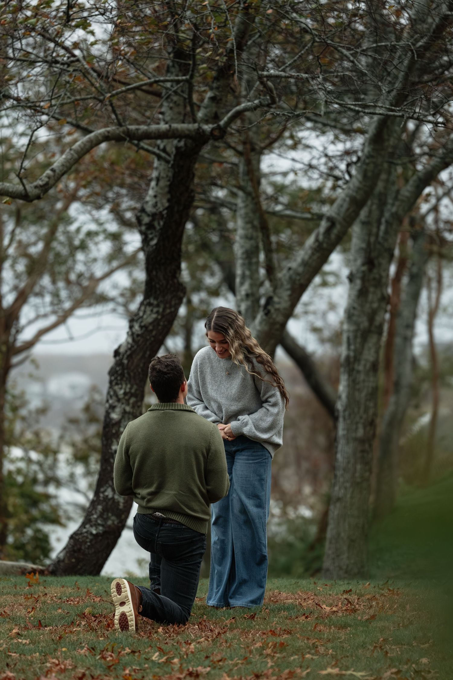 Two people having conversation on fallen leaves under autumn trees.