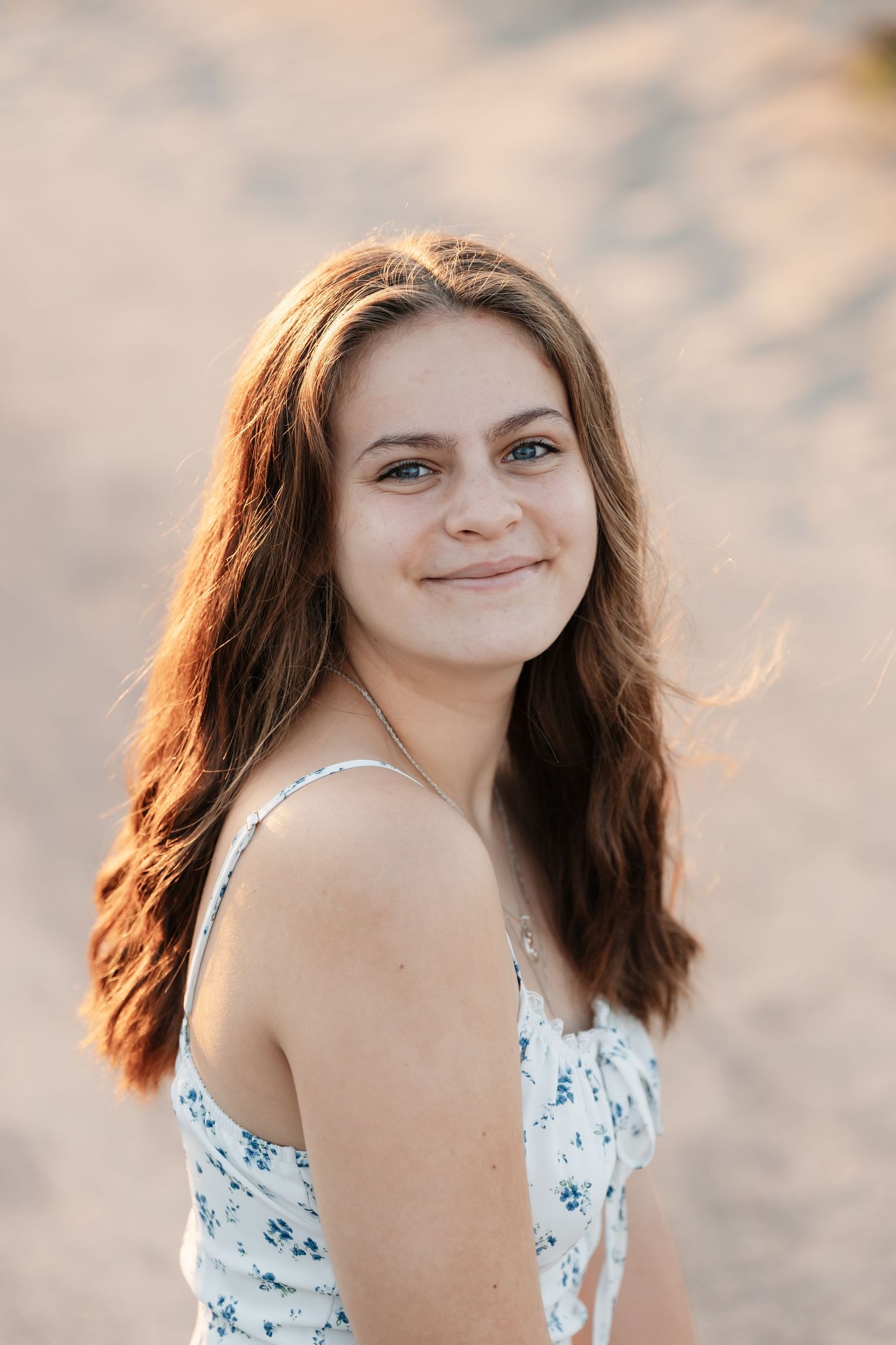 Close-up portrait showing genuine smile while wearing a floral summer dress.