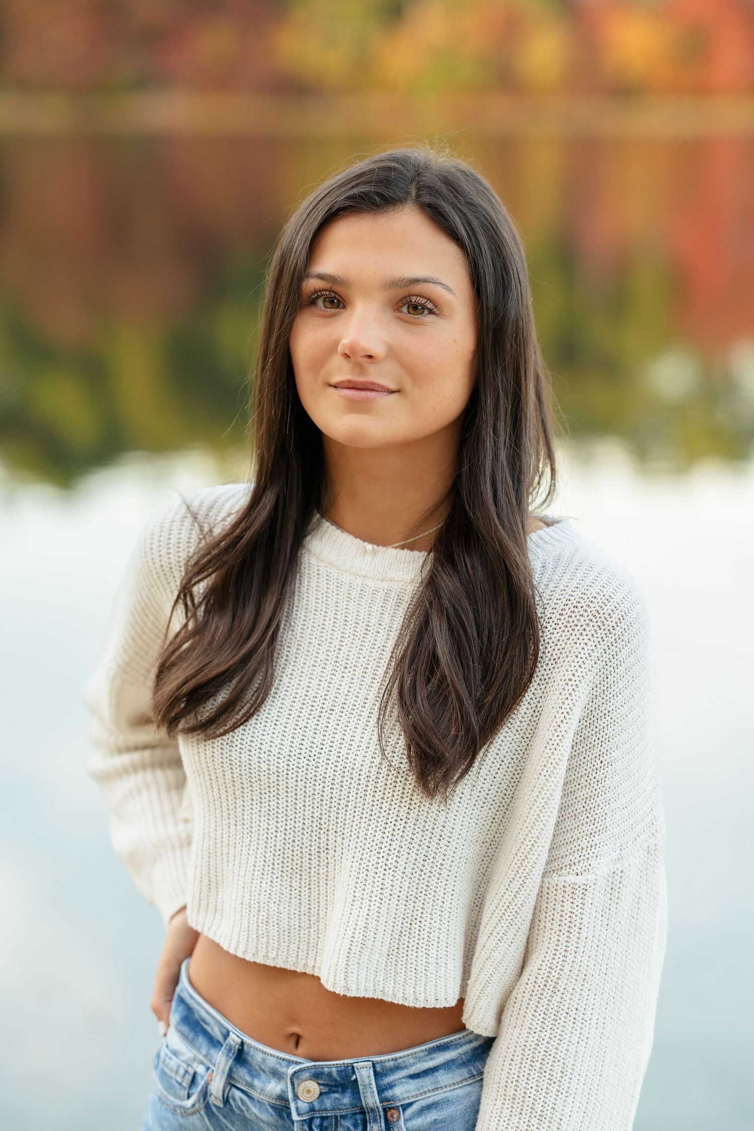 Fall portrait by lake wearing white knit sweater and jeans.