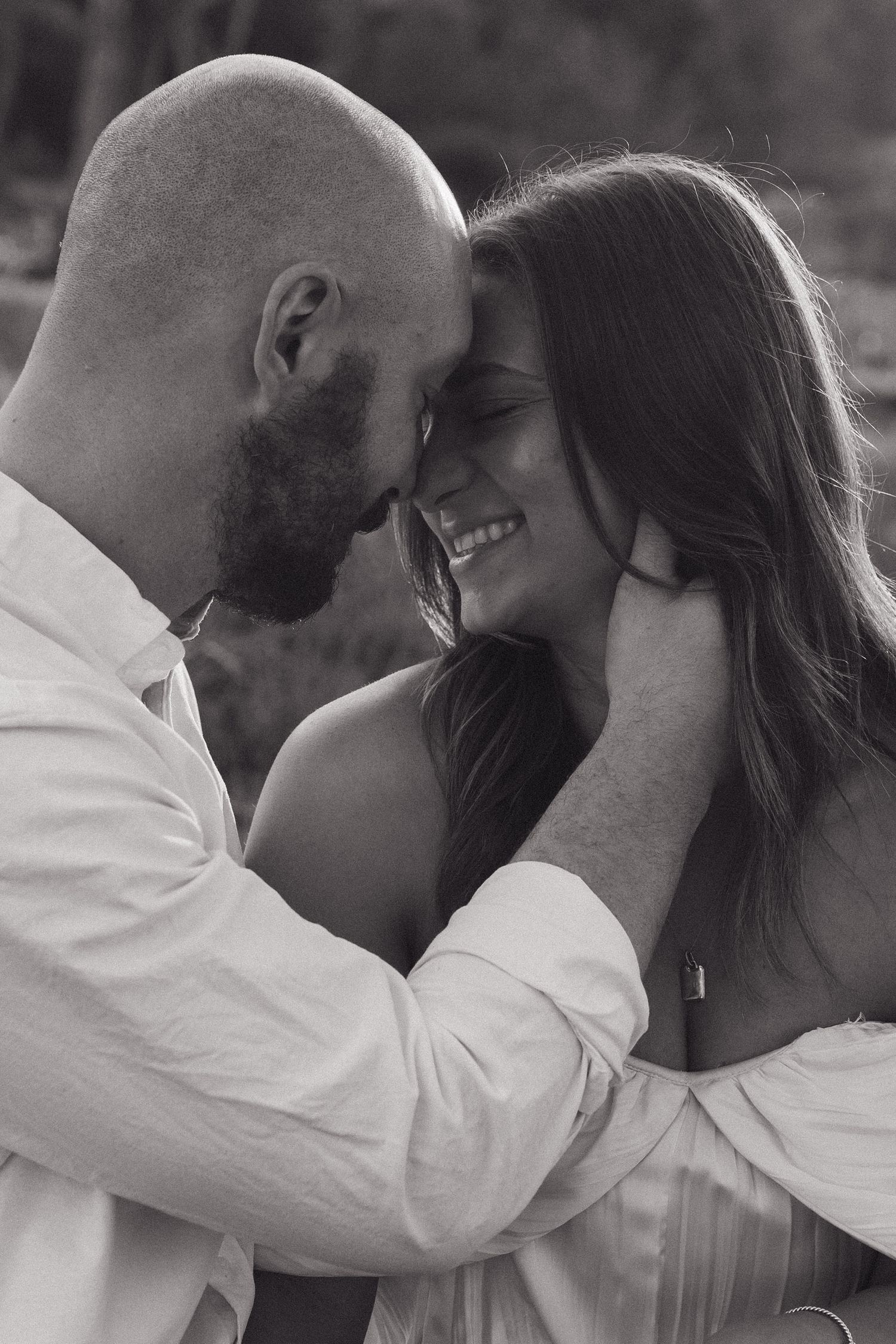 Intimate black and white portrait of a couple sharing a tender moment outdoors.