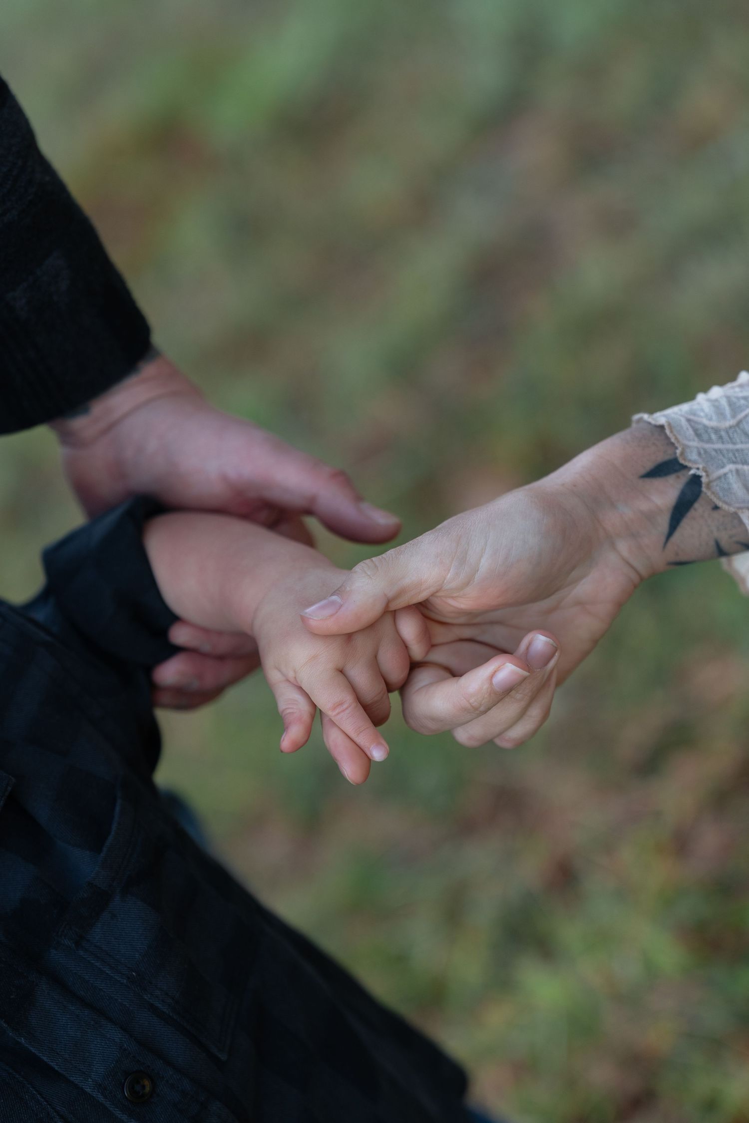 Close-up of hands reaching and touching each other against blurred natural background.