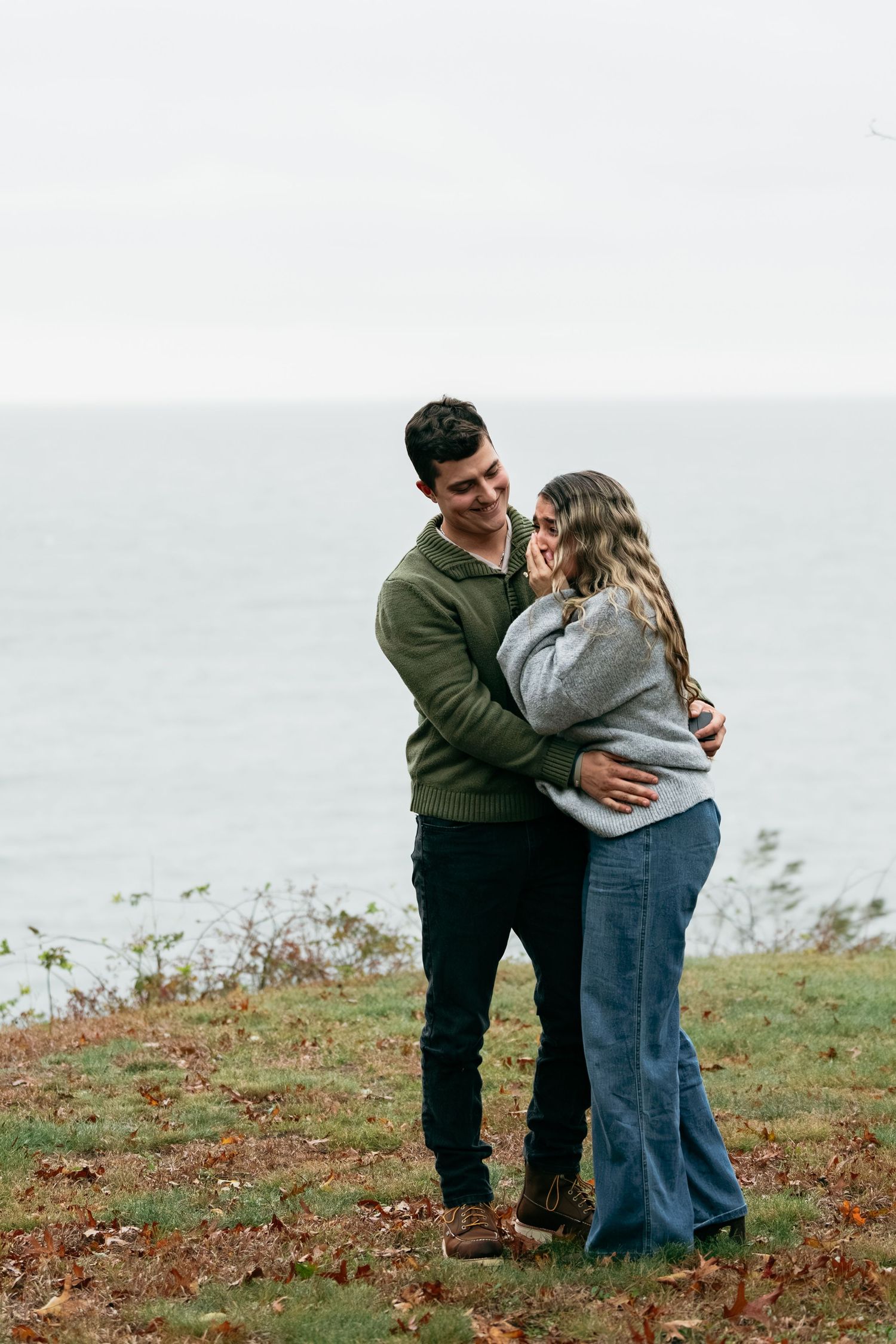 A couple shares a romantic moment on a cliff overlooking the ocean.