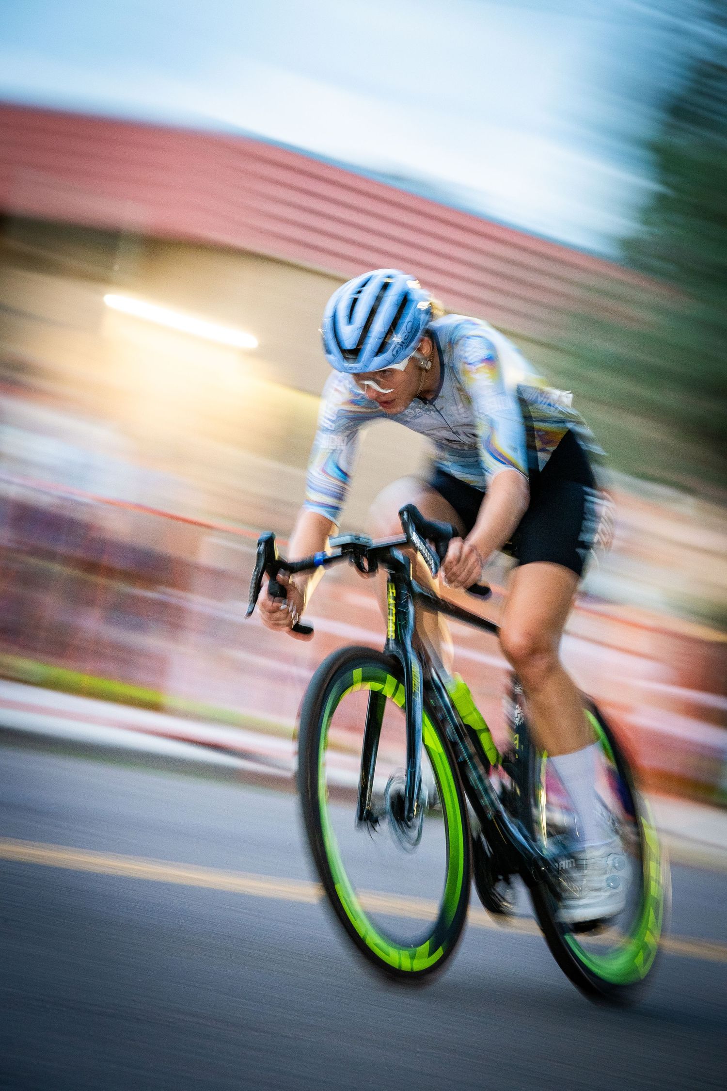 Female cyclist racing at high speed during the Littleton Twilight Criterium in Colorado, captured with motion blur for a dynamic effect.
